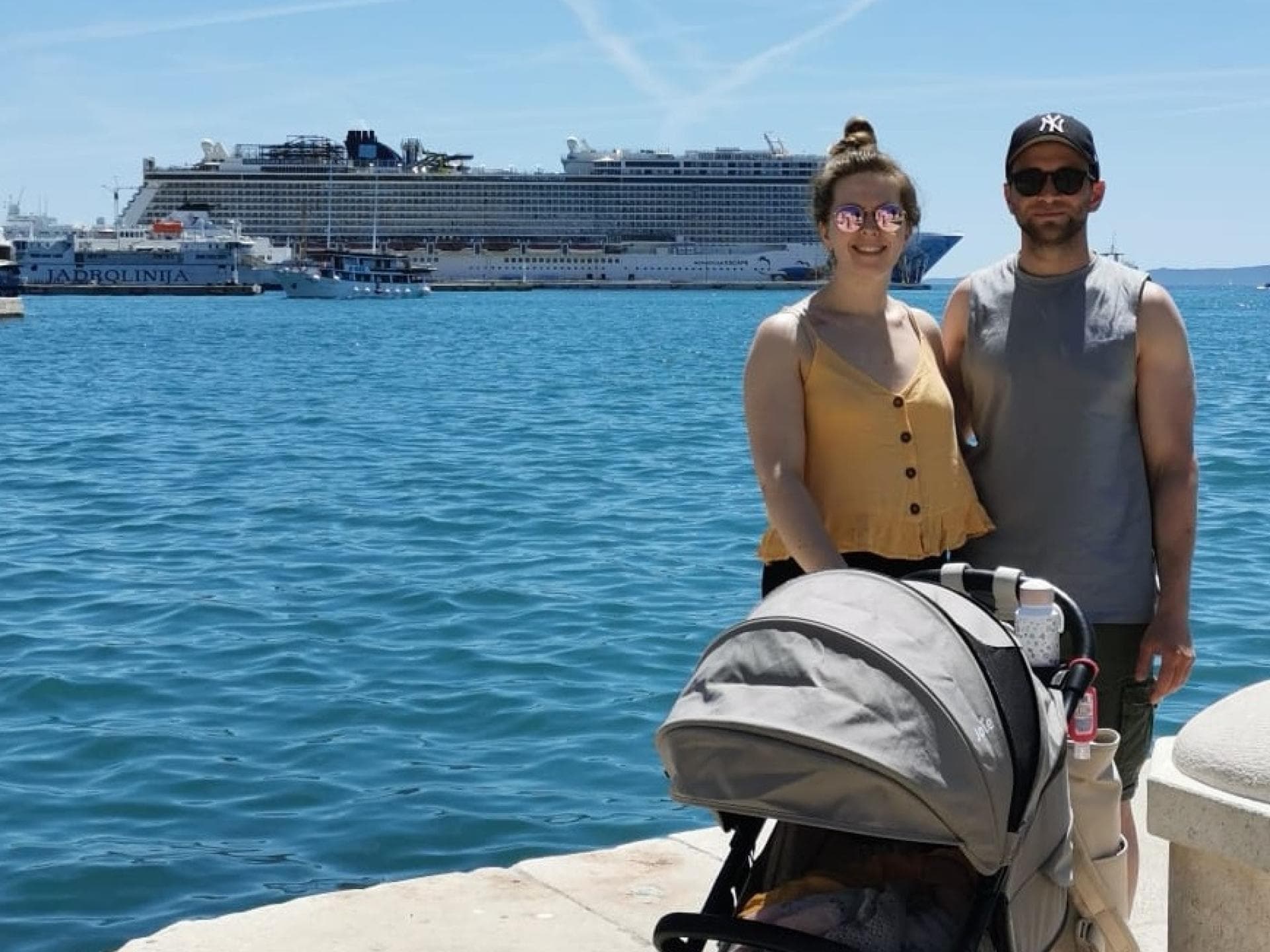 Unsere Autorin, ihr Mann und ihr Kind im Buggy stehen am Hafen in Split vor dem Kreuzfahrtschiff Norwegian Escape.