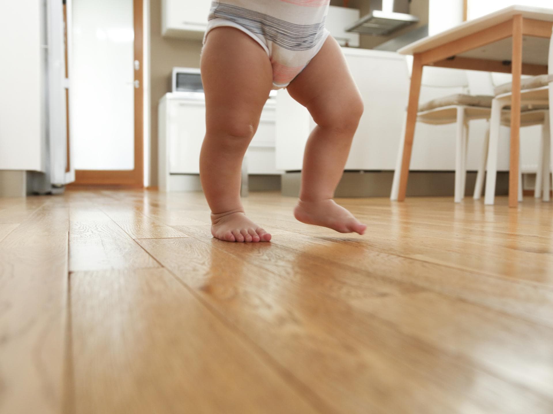 Babybeine beim Laufen in der Küche.