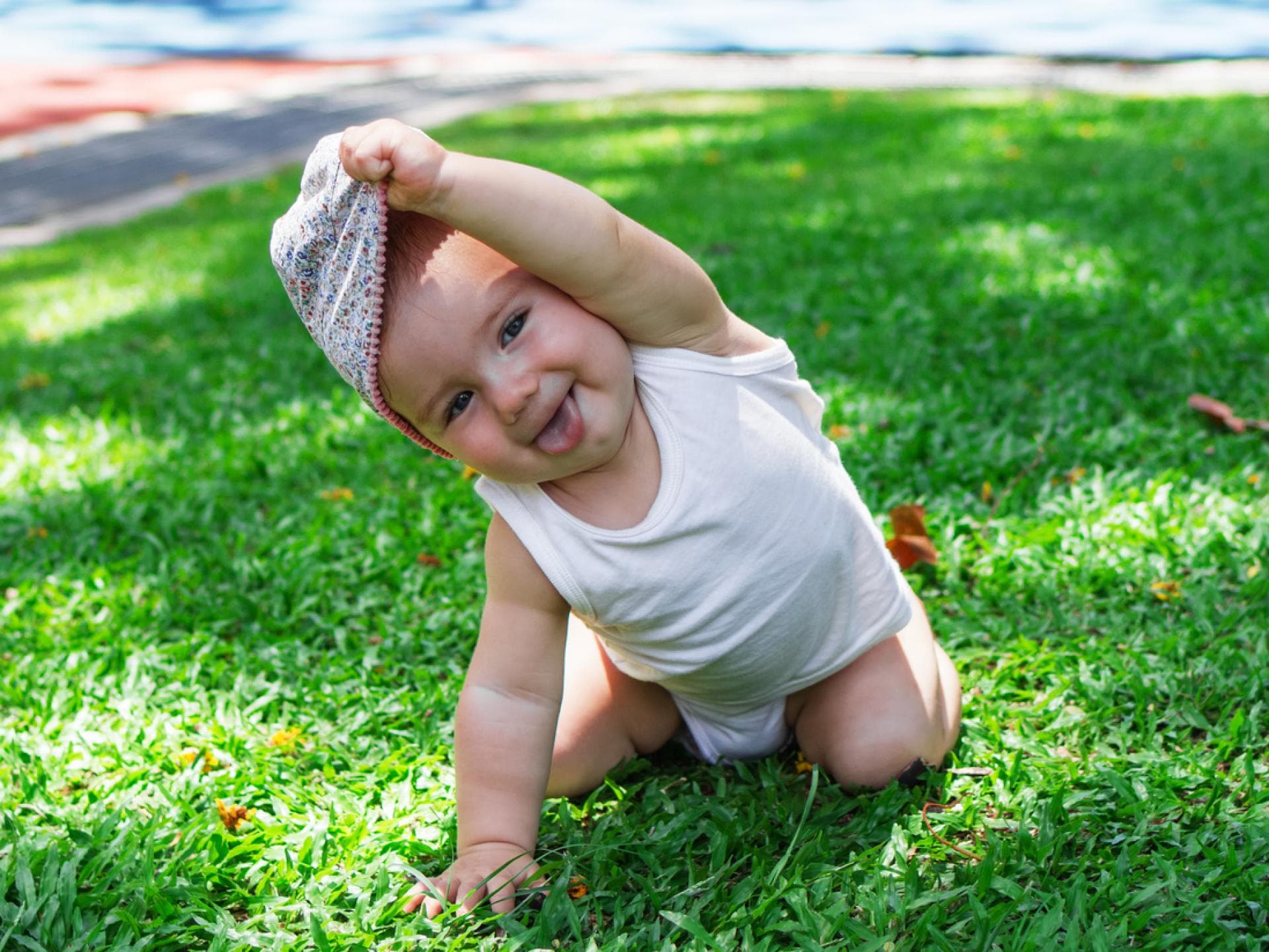 Ein kleines Baby, das sich die Mütze vom Kopf zieht.