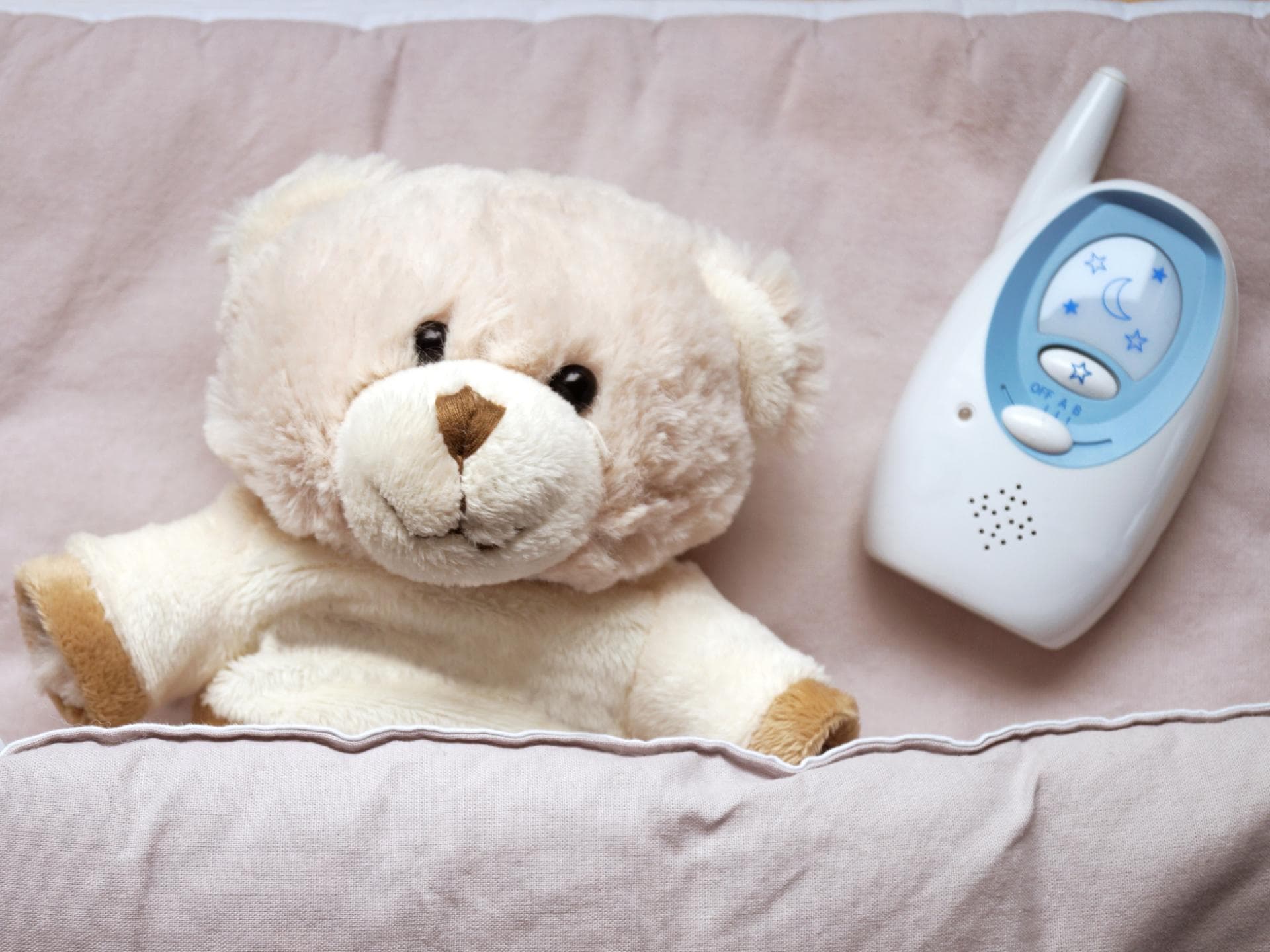 Ein Teddy liegt neben einem Babyphone. 