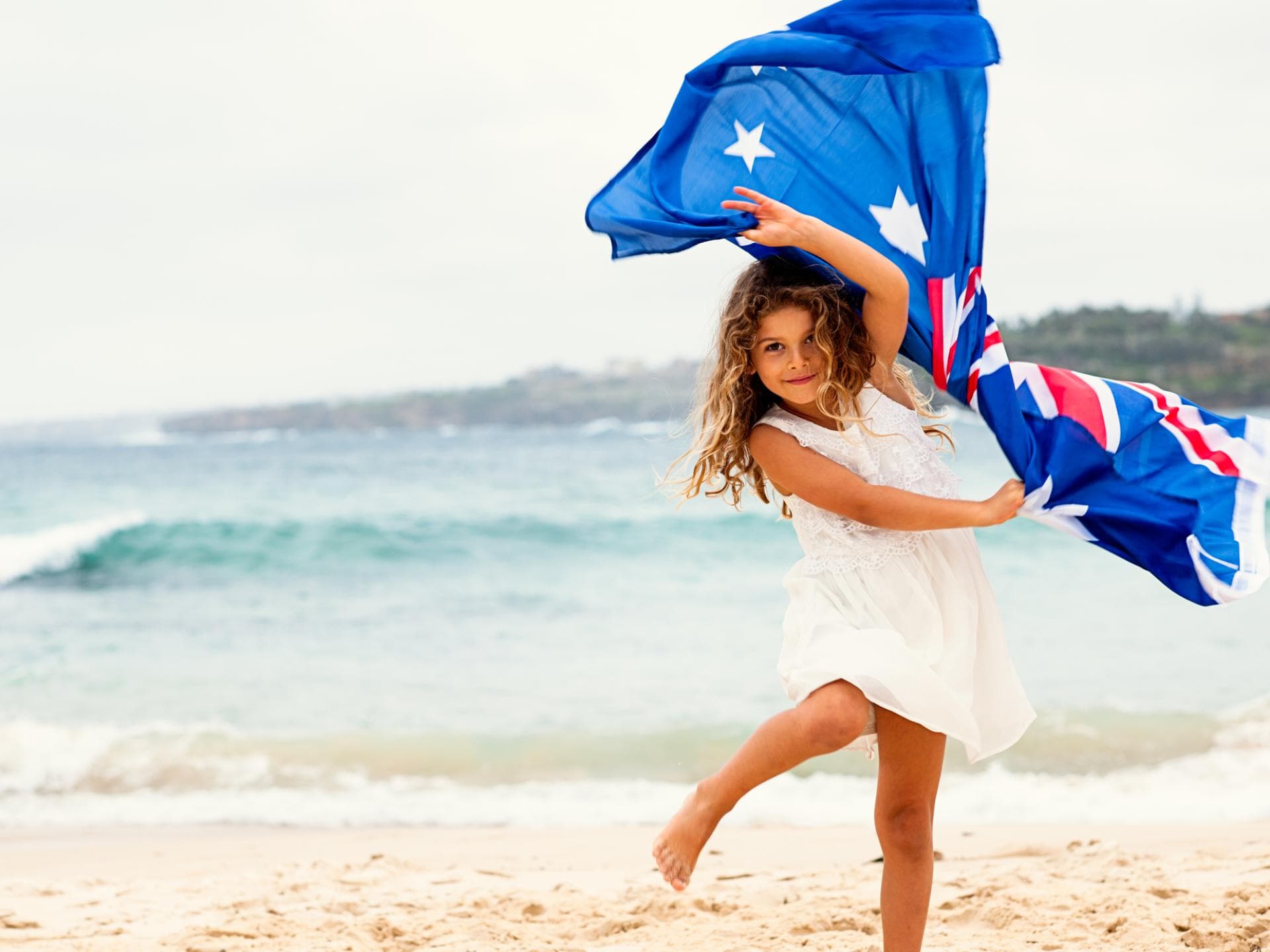Ein Mädchen mit australischer Flagge am Strand. 