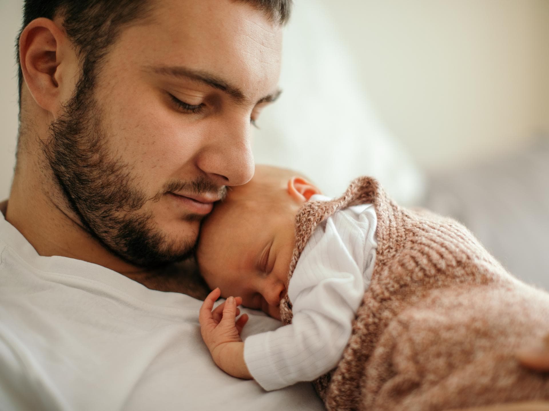 Studie zeigt: Das Gehirn von Vätern schrumpft bei der Geburt des ersten Kindes. Kleines Baby schläft auf der Brust des Vaters.