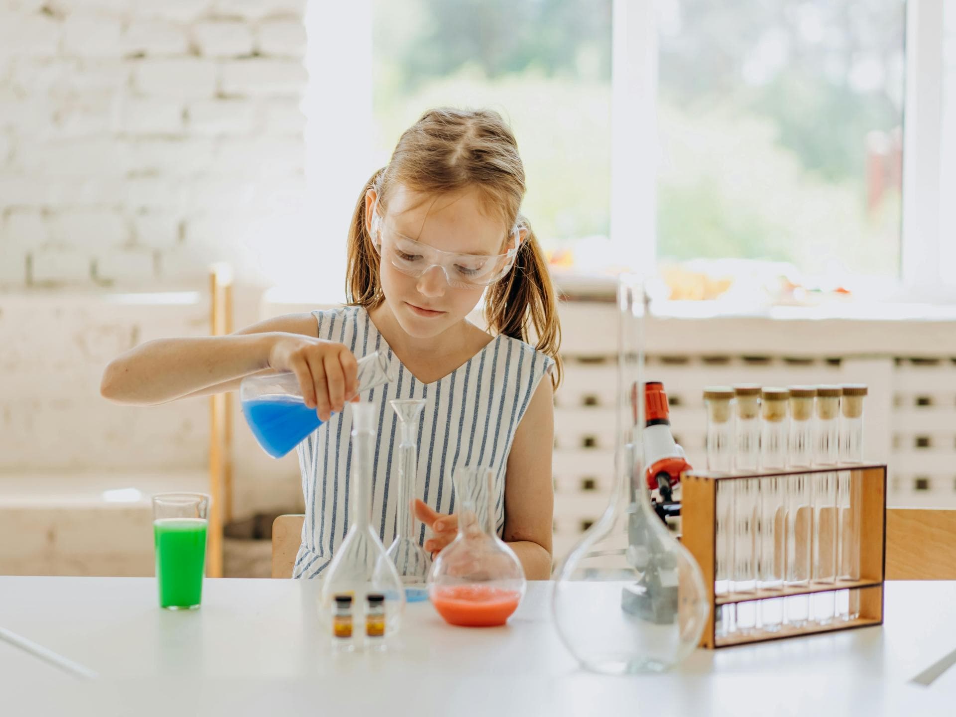 Mädchen experimentiert mit bunten Flüssigkeiten. 