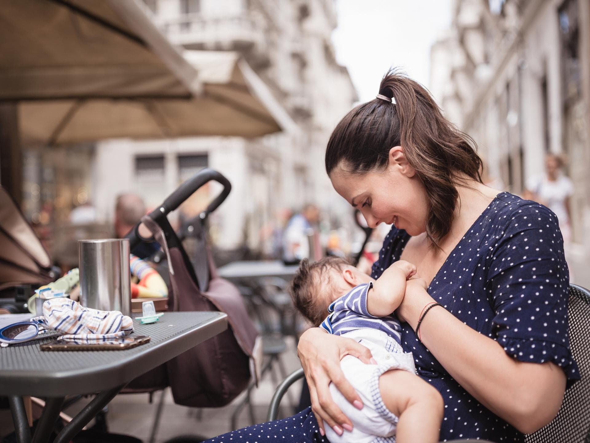 Beim Stillen in der Öffentlichkeit fühlen sich nicht alle Mütter wohl – leider! Eine Mutter stillt ihr Baby draußen in einem Café.