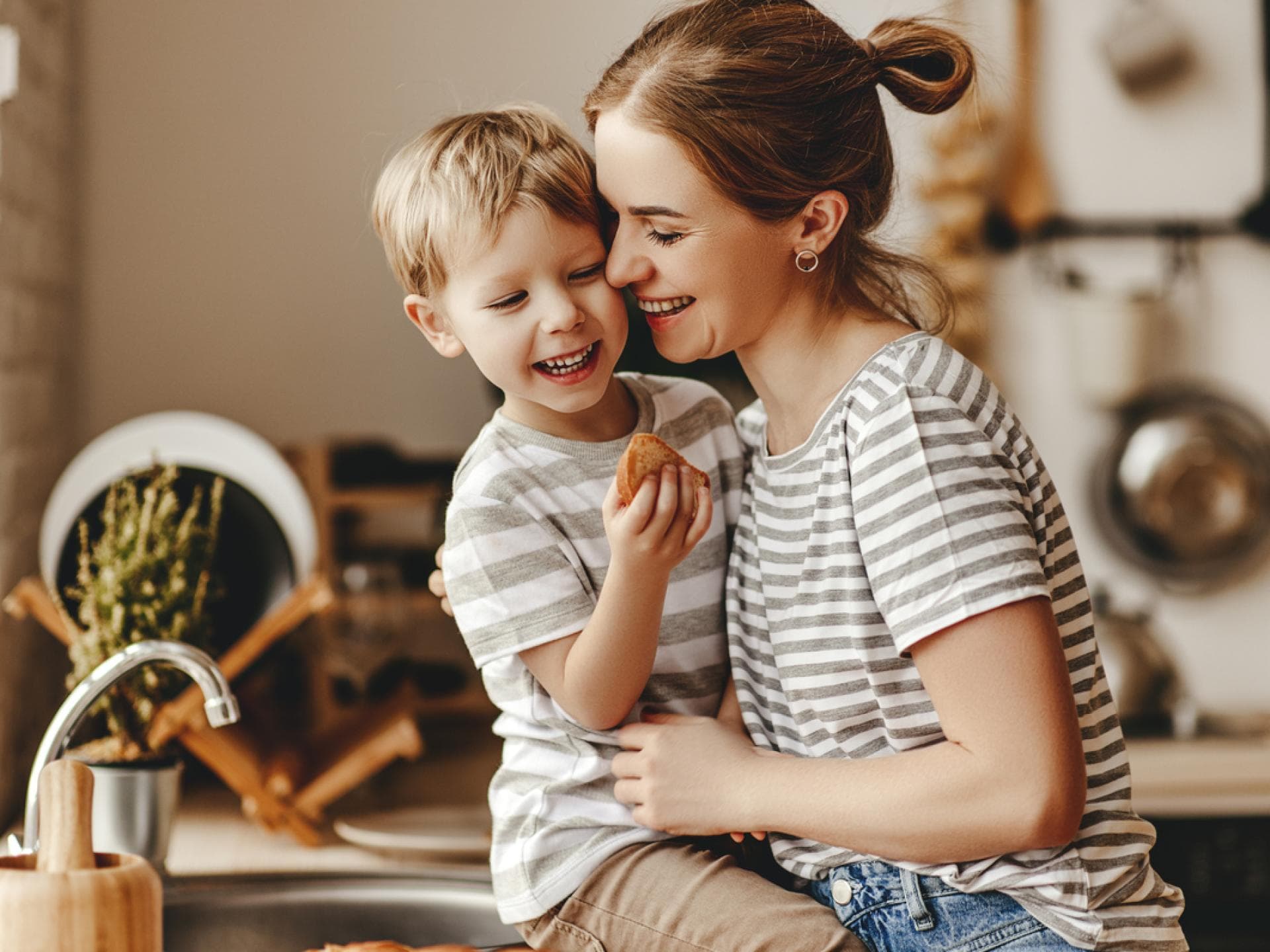 Durch aktives Zuhören helfen Eltern ihren Kindern am meisten. Mutter umarmt ihren Sohn in der Küche.