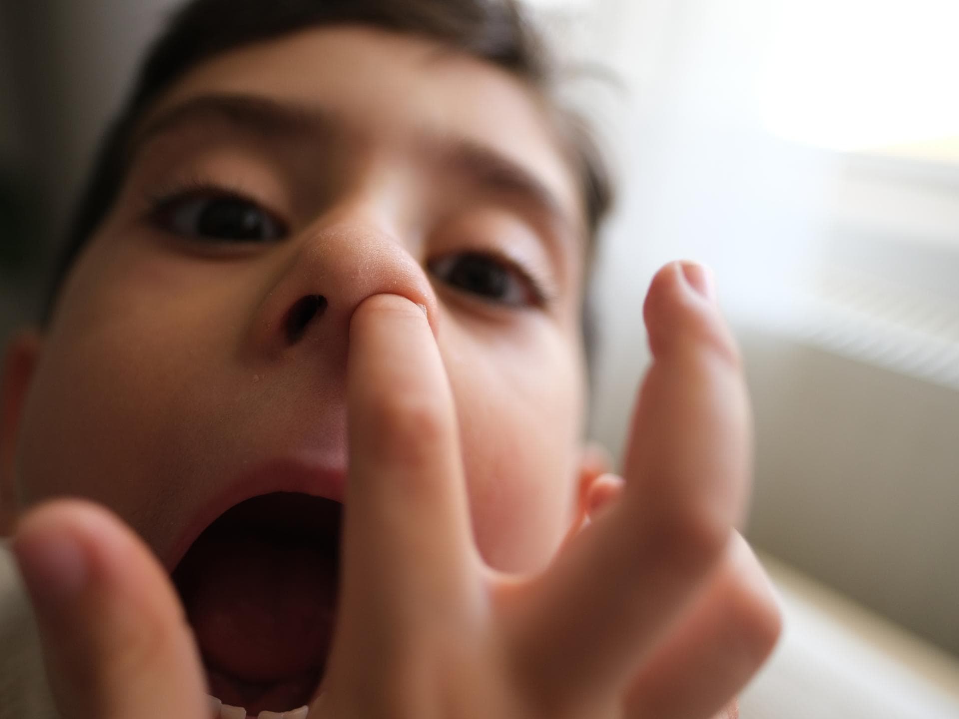 Eine Bügelperle in der Nase könnt ihr auch ohne Arzt wieder rausholen. Ein kleiner Junge steckt seinen Finger in die Nase.