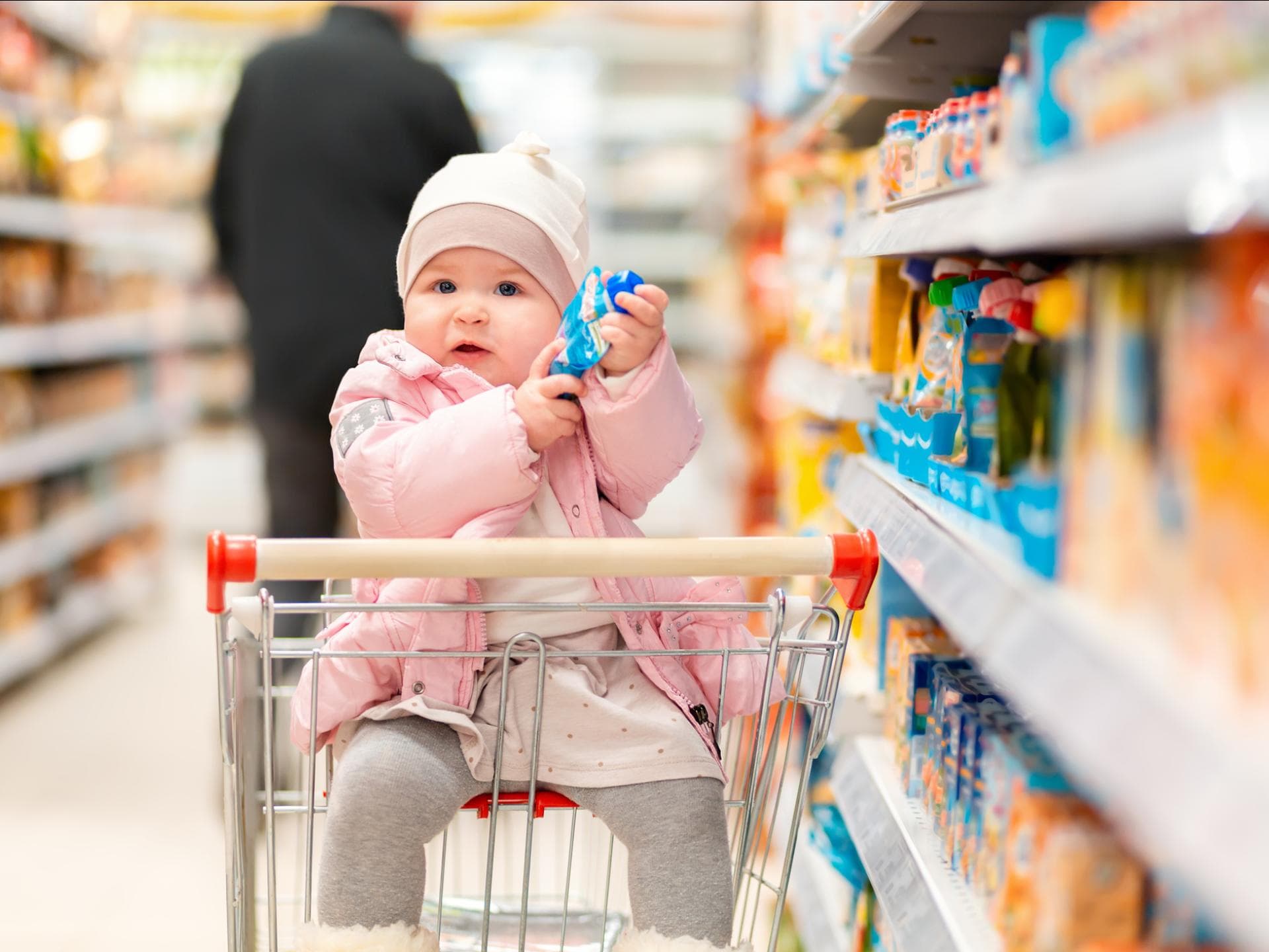 Sind Quetschies wirklich so ungesund wie ihr Ruf? Ein kleines Baby hat in einem Supermarkt einen Quetschie in der Hand.