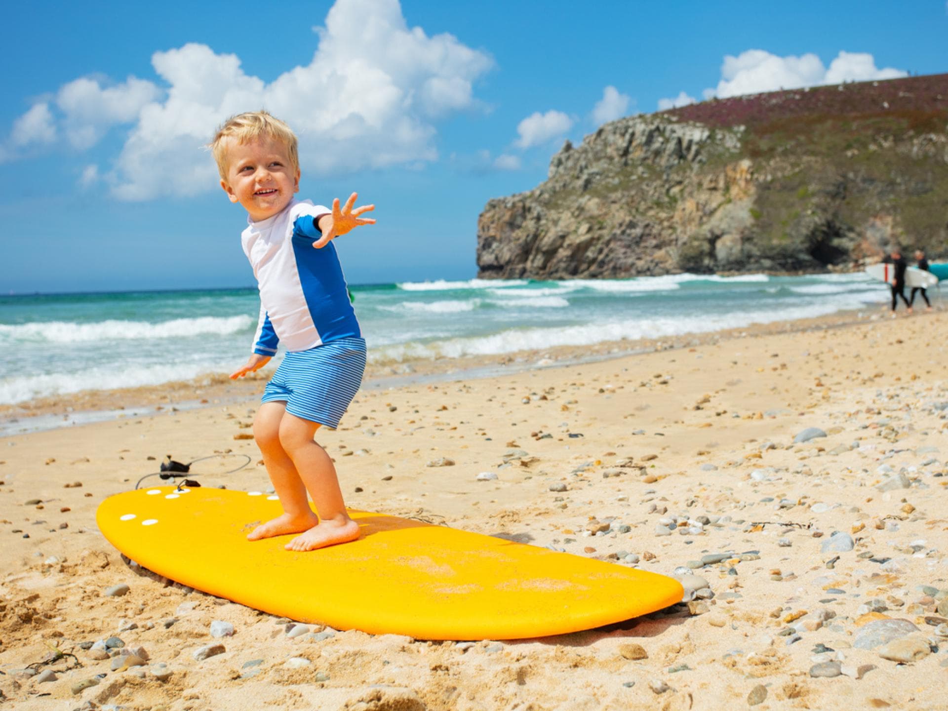 Kleiner Junge steht auf einem Surf-Brett.