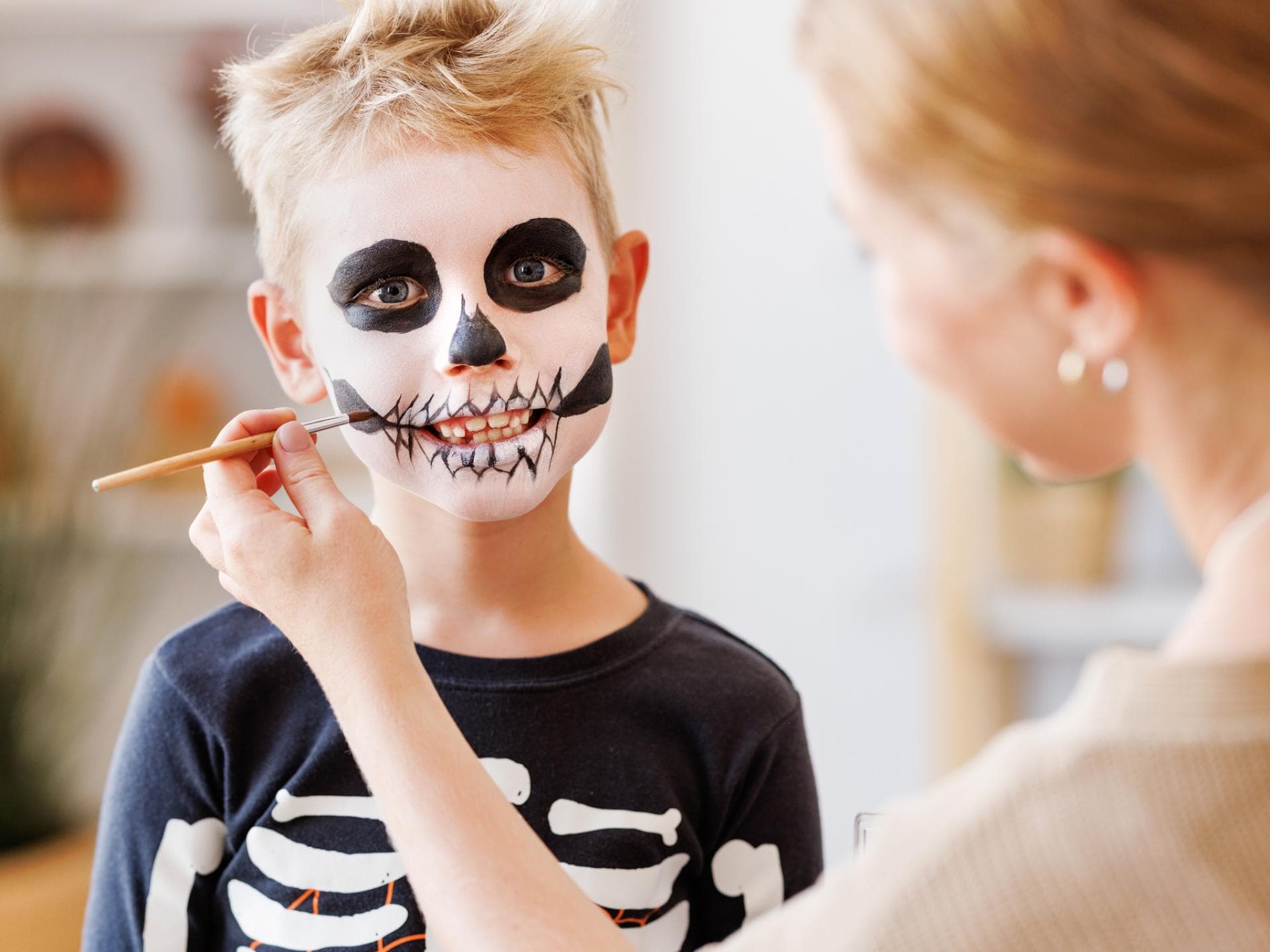 Mutter schminkt ihren Sohn als Skelett