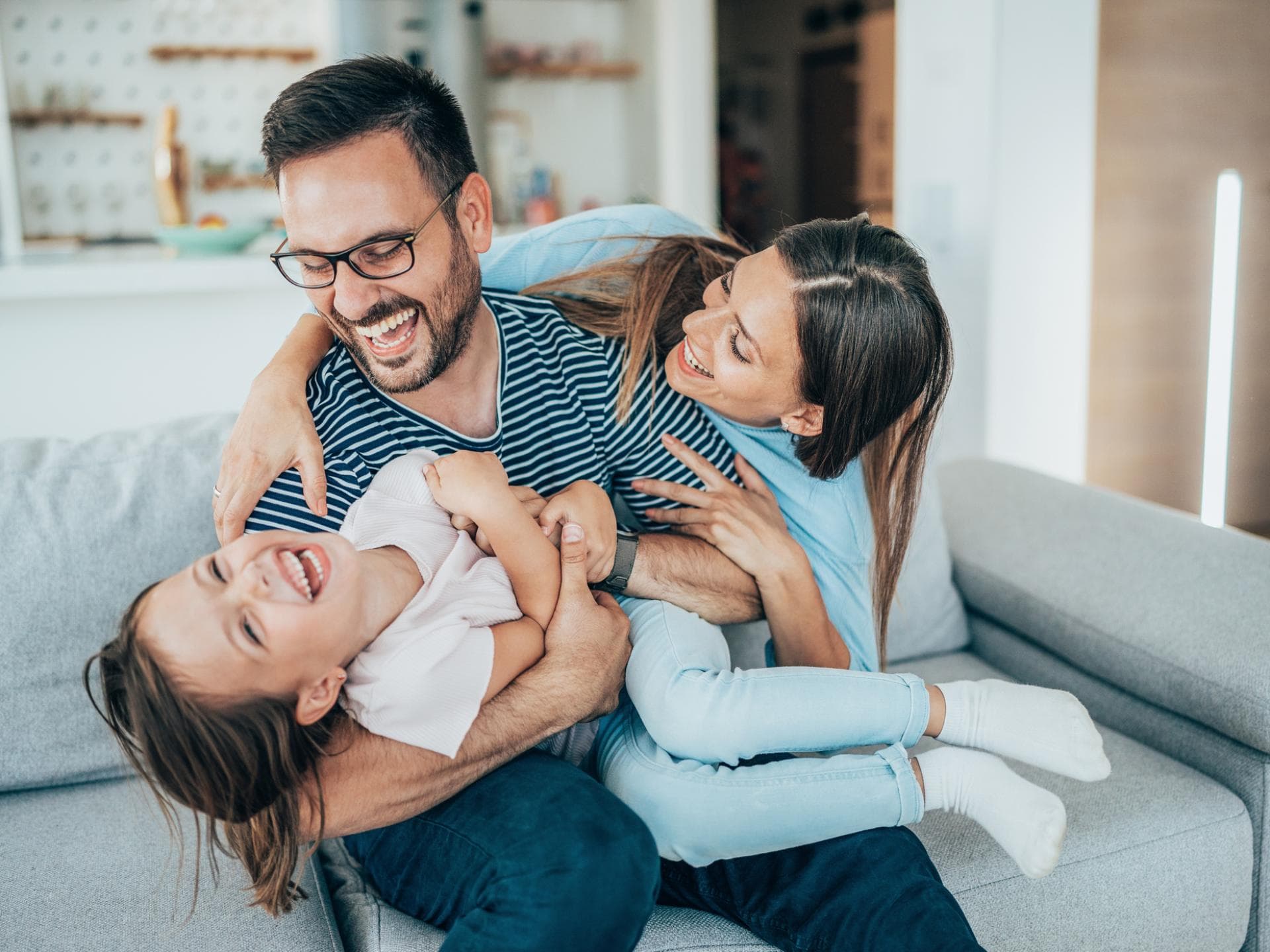 Fröhliche Familie tobt auf dem Sofa.