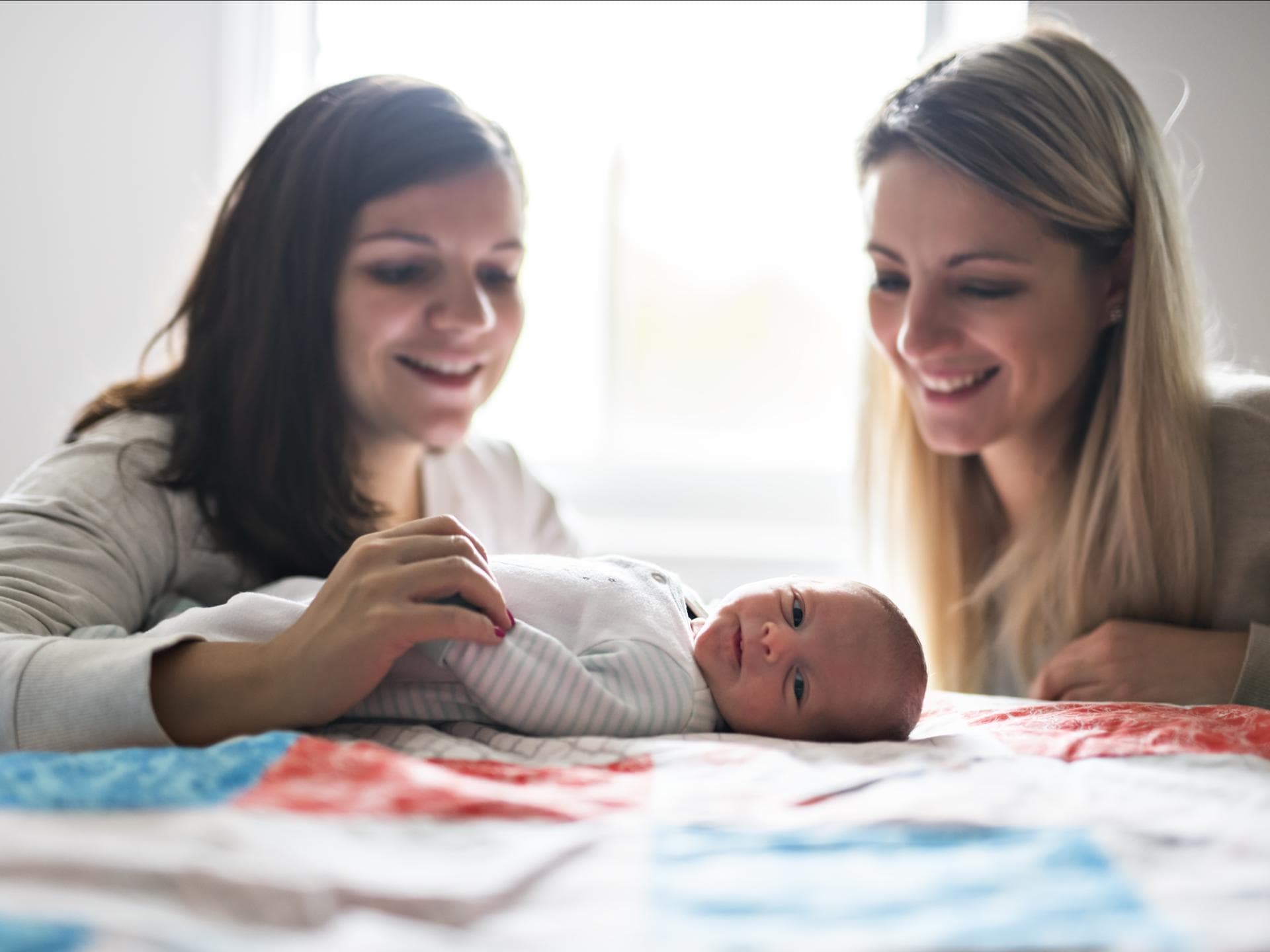 Zwei Frauen lächeln ein Baby an.