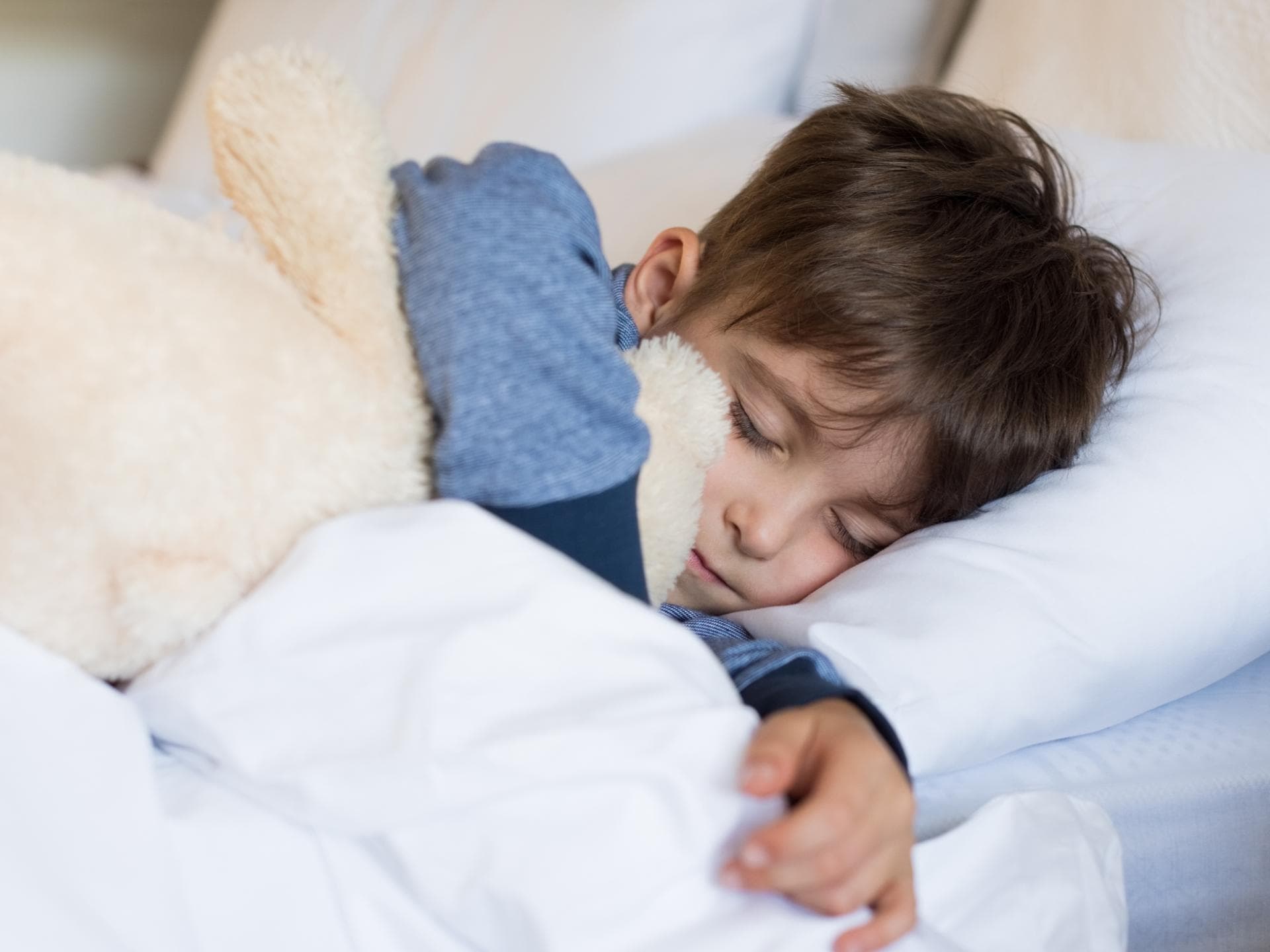 Manchmal nässen noch Fünfjährige nachts ein. Junge liegt im Bett und schläft.