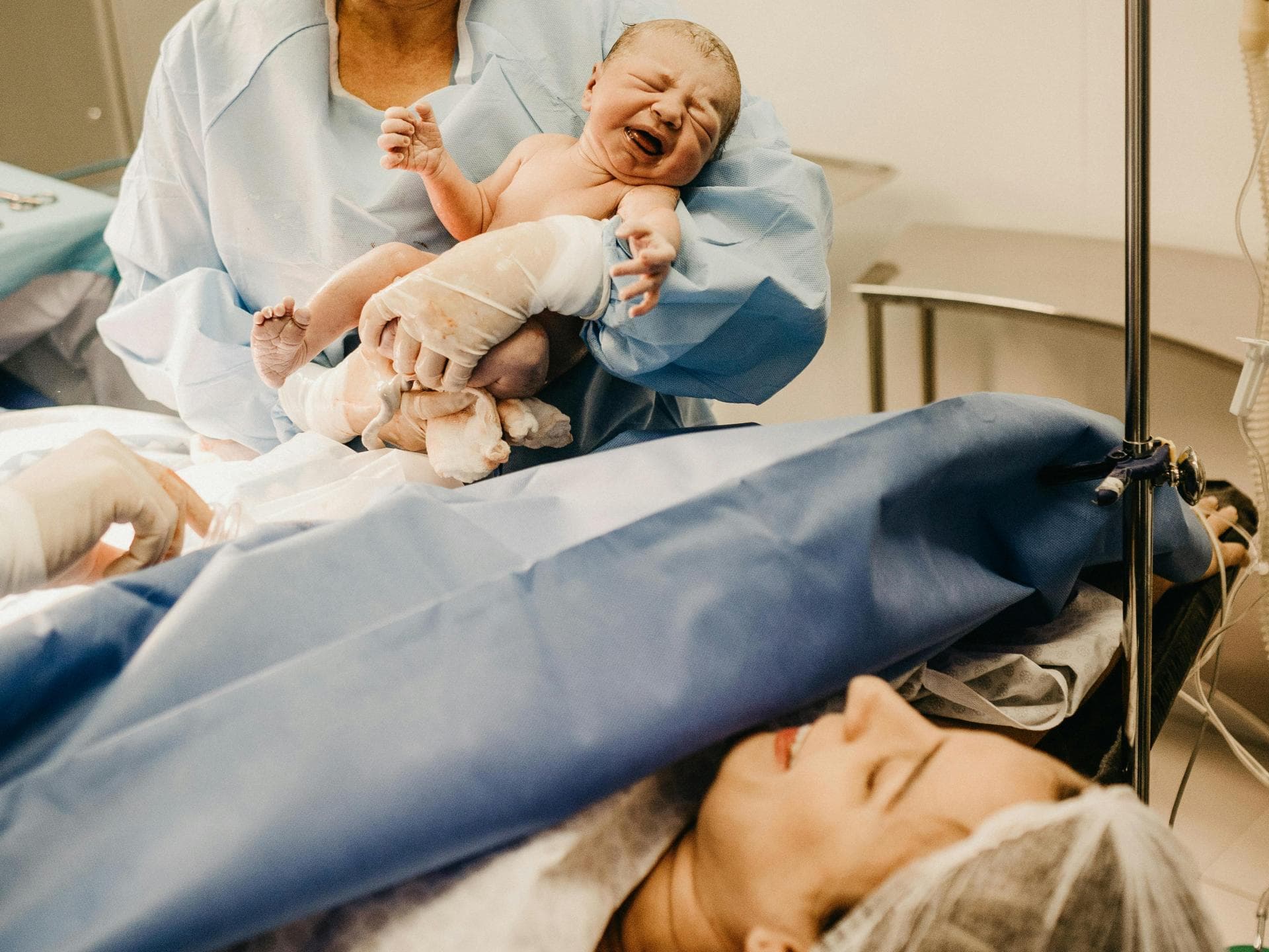 Mit einem Geburtsspiegel kann die Frau die Geburt live beobachten. Eine Frau im Kreißsaal hat gerade ihr Baby bekommen