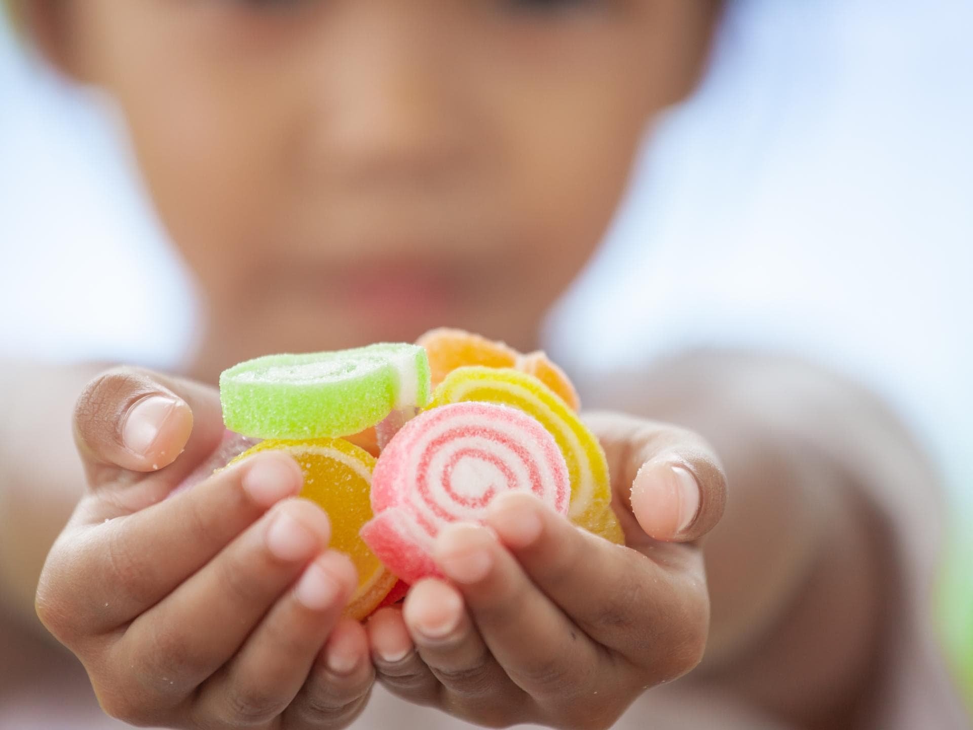 Viele Zuckerfallen werden von Momfluencerinnen als gesund beworben. Kind hält Fruchtgummis in der Hand.