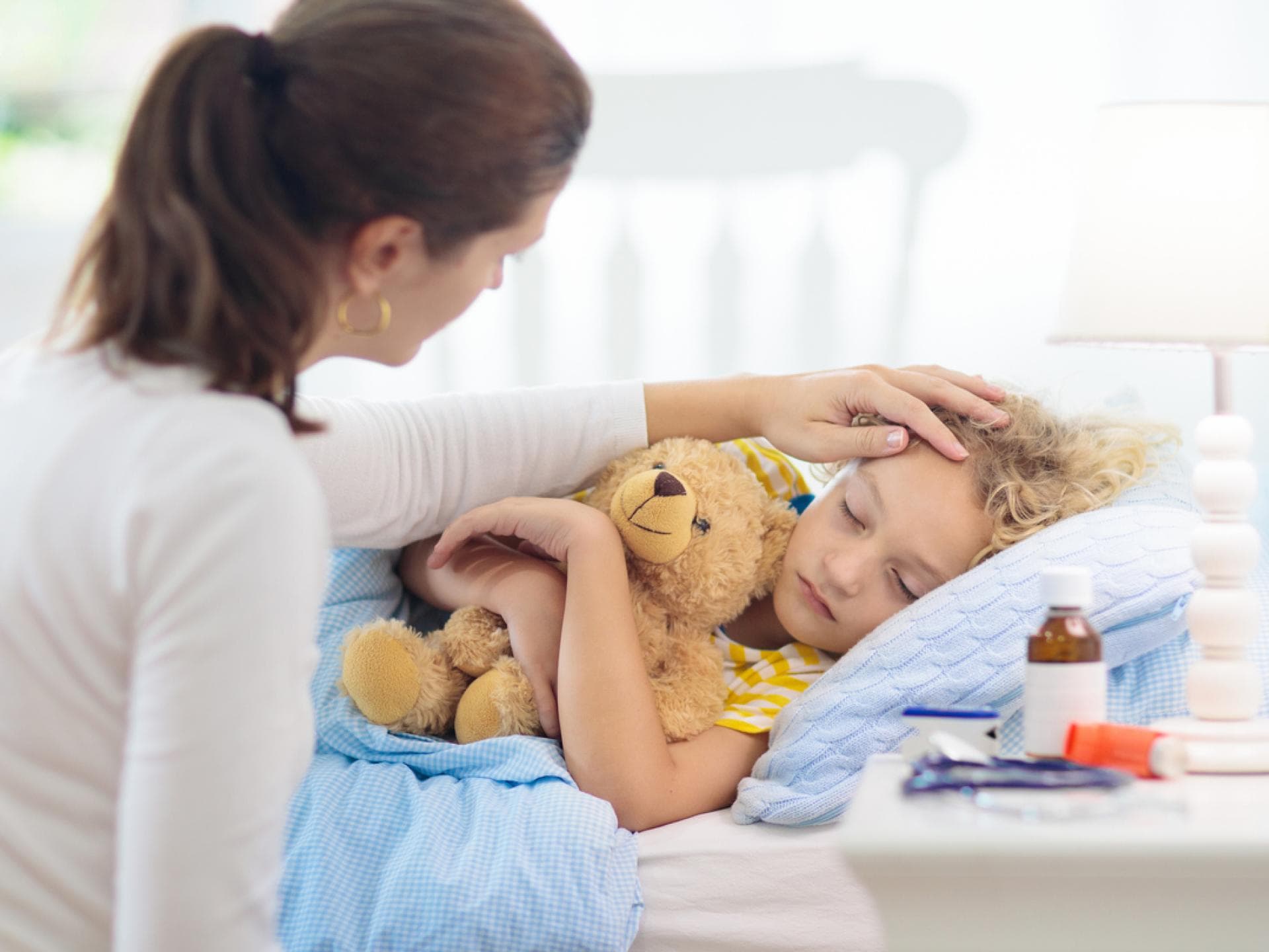 Mutter sitzt neben ihrem kranken Kind am Bett.