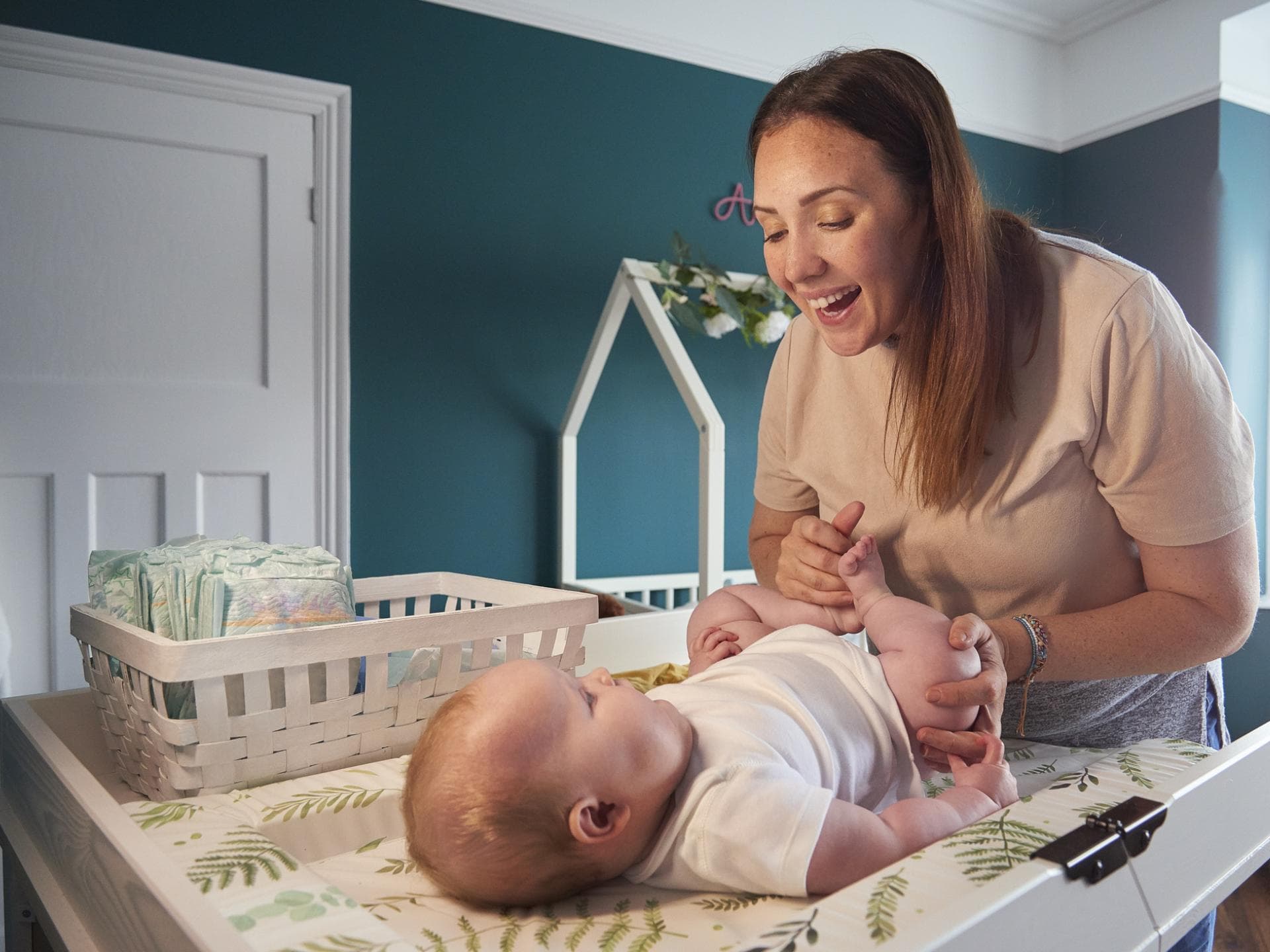 Eine Mutter wechselt ihrem Baby auf einer Wickelkommode die Windel. 