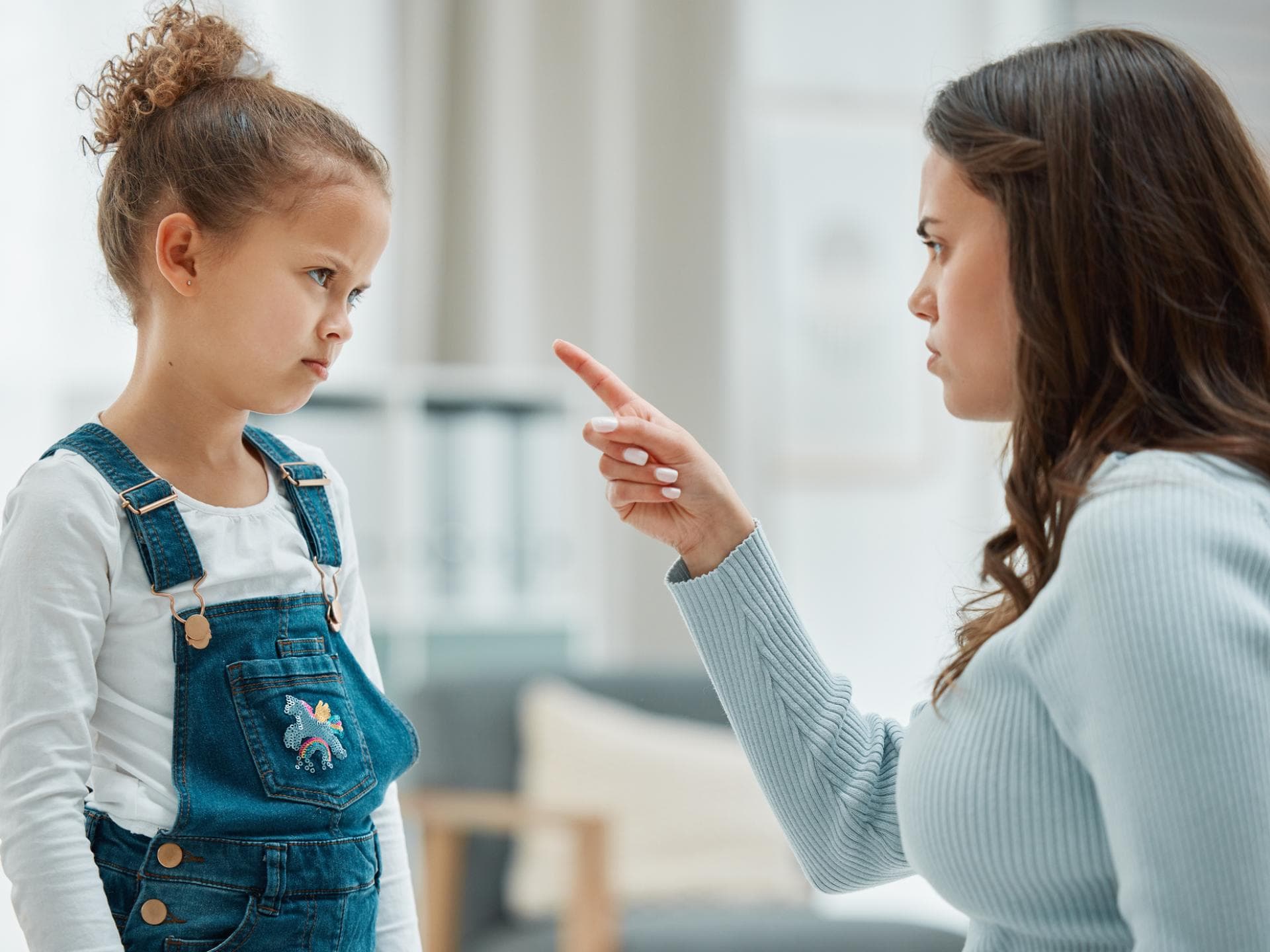 Sind Eltern zu streng, kann das negative Auswirkungen haben. Mutter schimpft mit erhobenem Zeigefinder mit ihrer Tochter.