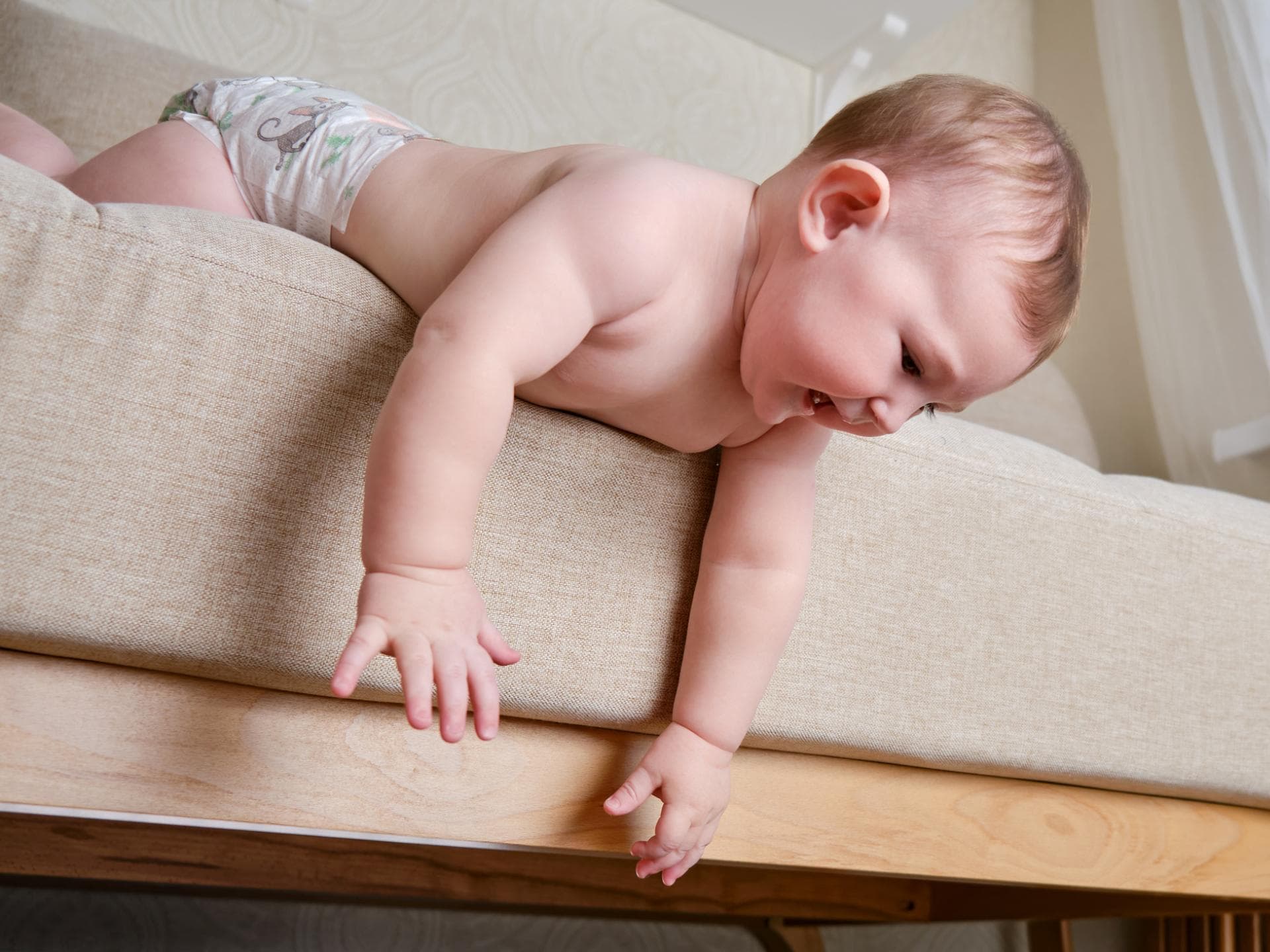 Baby beugt sich über den Bettrand.