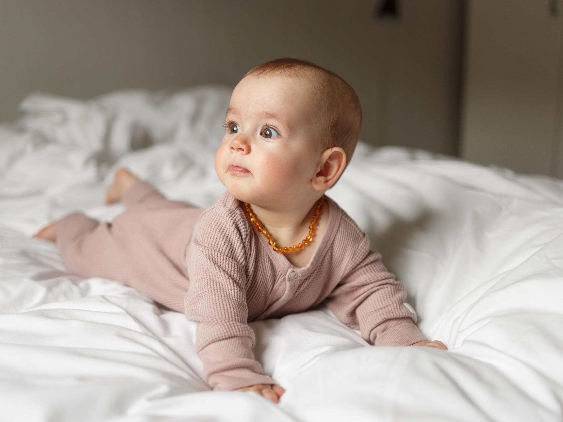 Ein Baby trägt eine Bernsteinkette um den Hals.