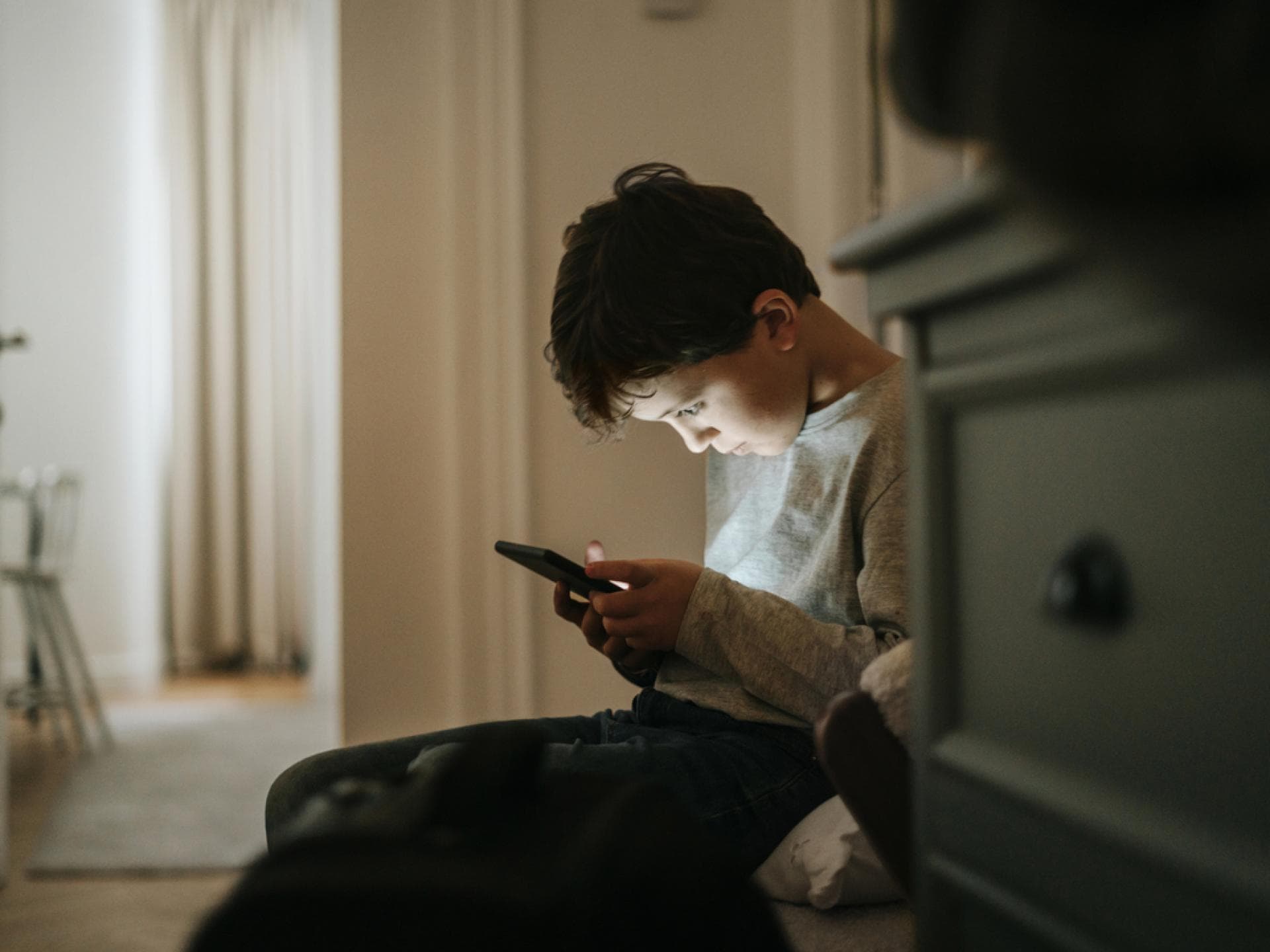 Digitale Medien können sich negativ auf die psychische Gesundheit auswirken. Junge beugt sich über sein Smartphone.