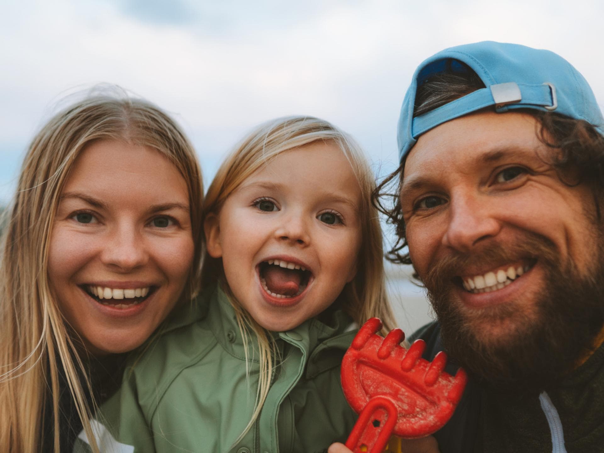 Auch Eltern erreichen ständig neue Meilensteine. Mama, Papa und Kind lachen in die Kamera.