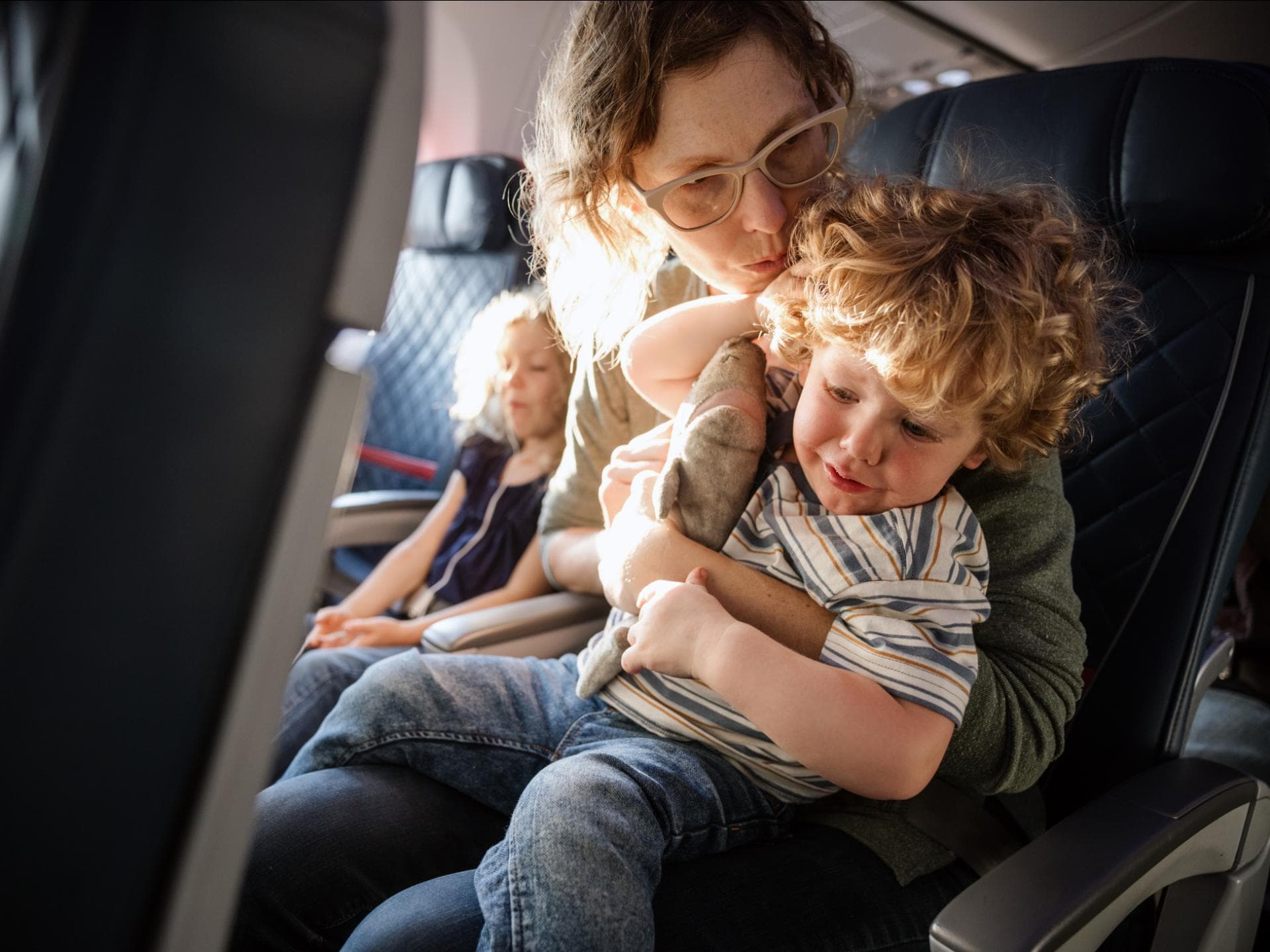 Eine Mutter tröstet ihr Kind im Flugzeug, das Ohrenschmerzen hat. 