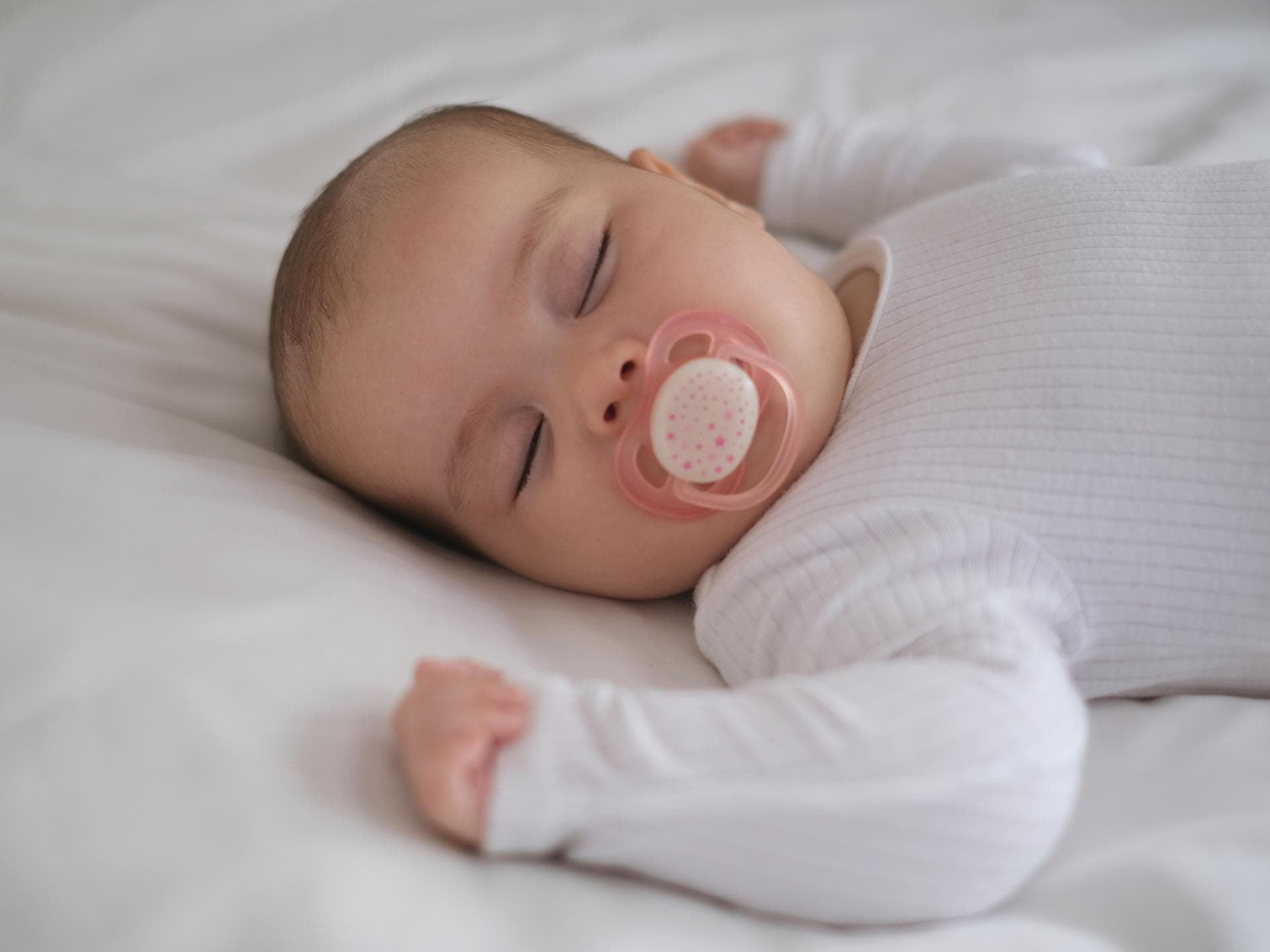 Schlafendes Baby mit Schnuller im Bett