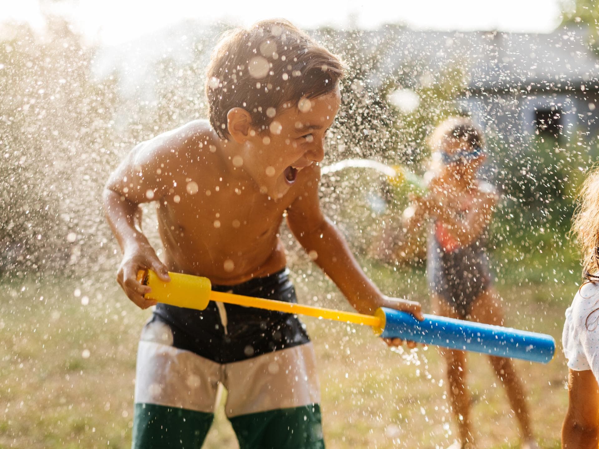Manche Sommeraktivitäten können Gefahren bergen. Junge spielt im Garten mit Wasserpistole.