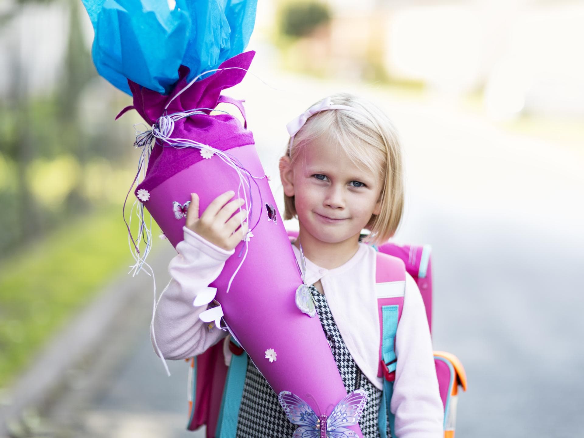 Ein kleines Mädchen hält eine Schultüte in der Hand. 