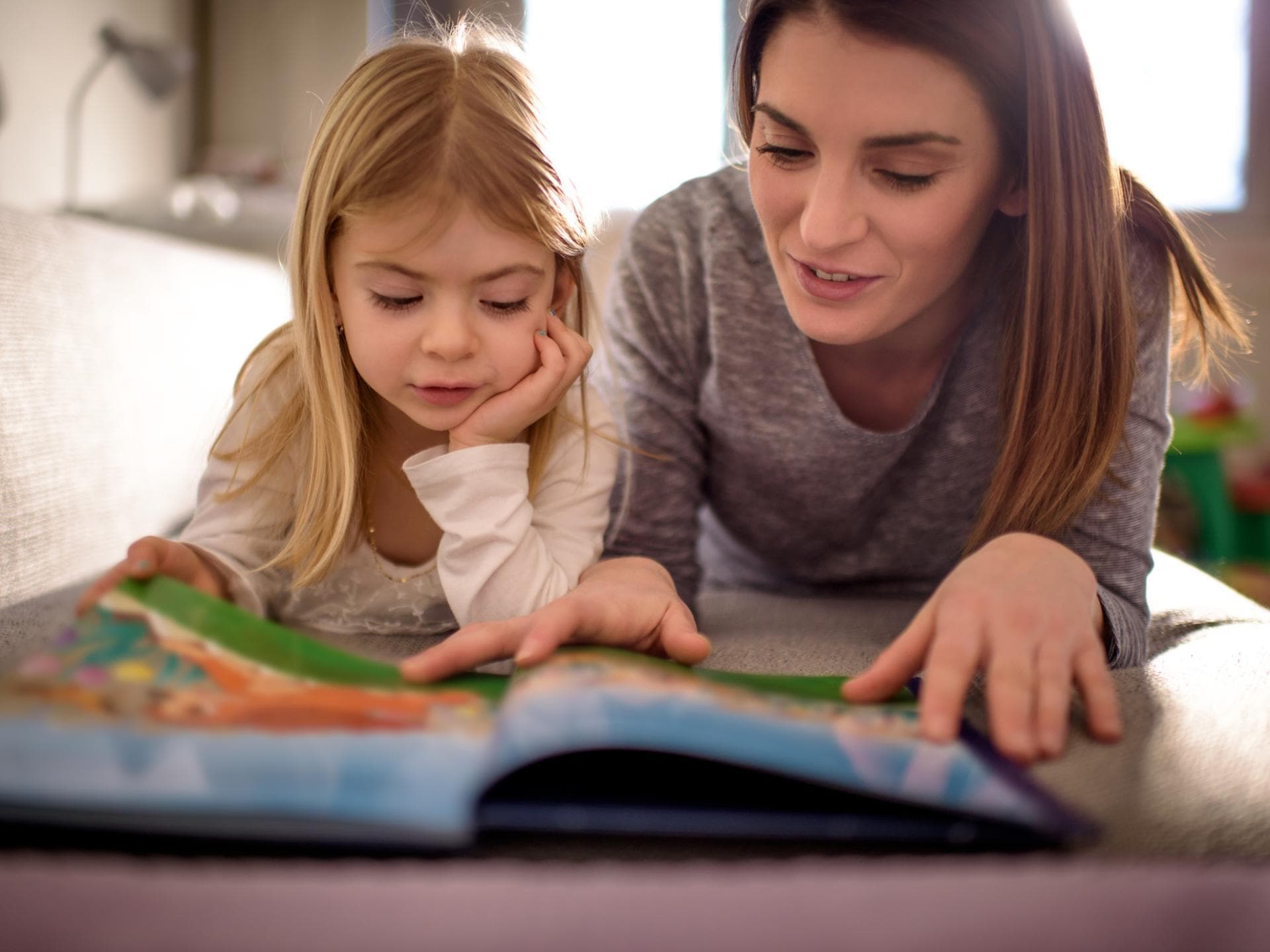 Mutter und Kind lesen gemeinsam auf dem Fußboden.