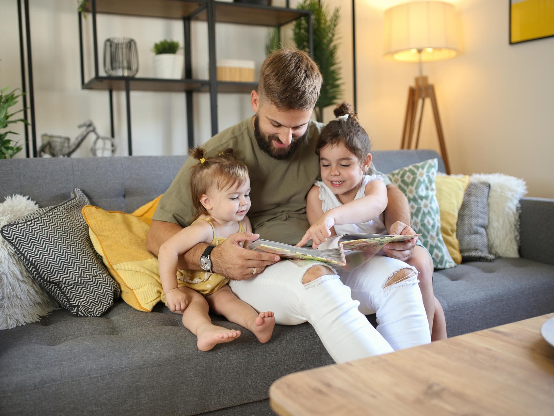 Vater schaut sich mit zwei Kindern Fotoalbum an.