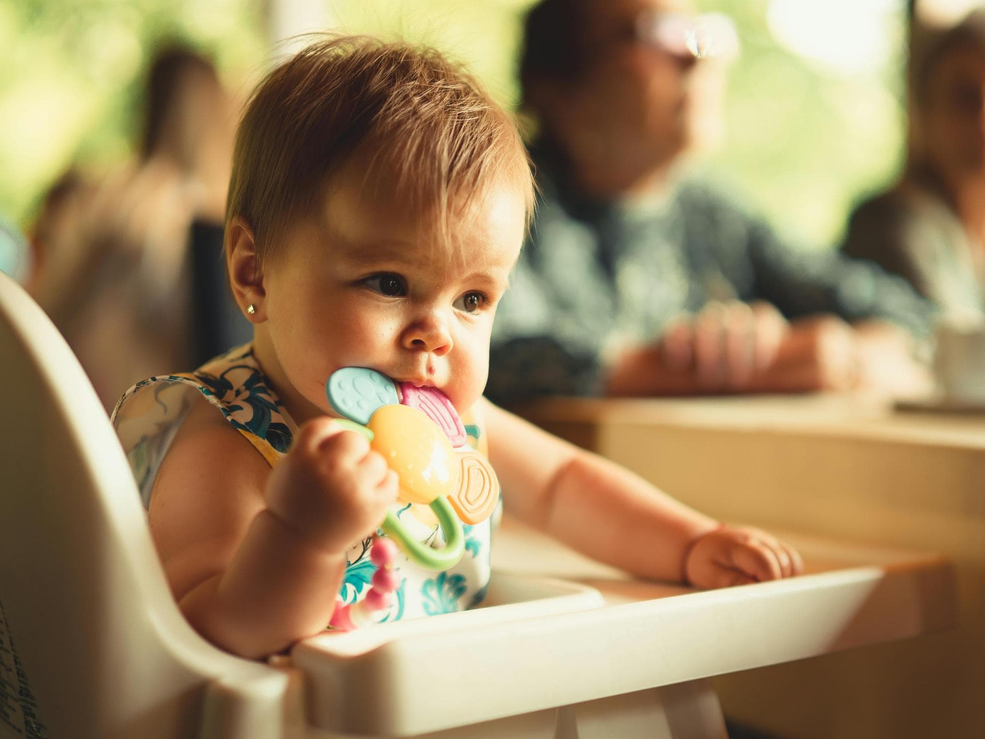Baby im Hochstuhl kaut auf einem Beißring