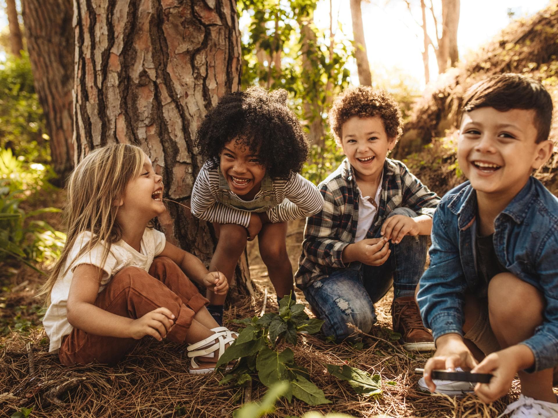 Vier Kinder lachend im Wald.