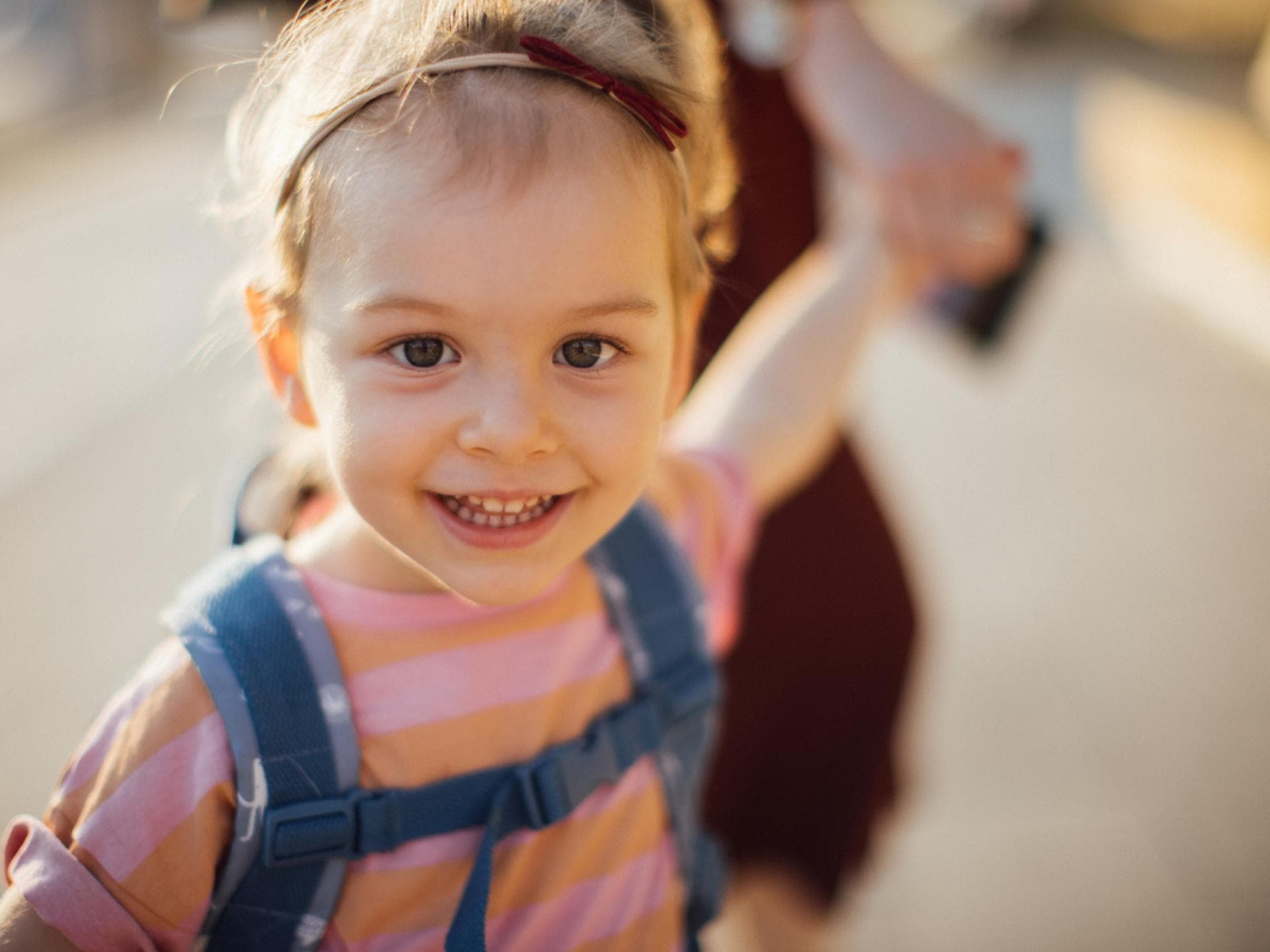 Für einen gelungenen Kita-Start gilt es ein paar Fehler zu vermeiden. Mädchen mit Kita-Rucksack an der Hand ihrer Mama