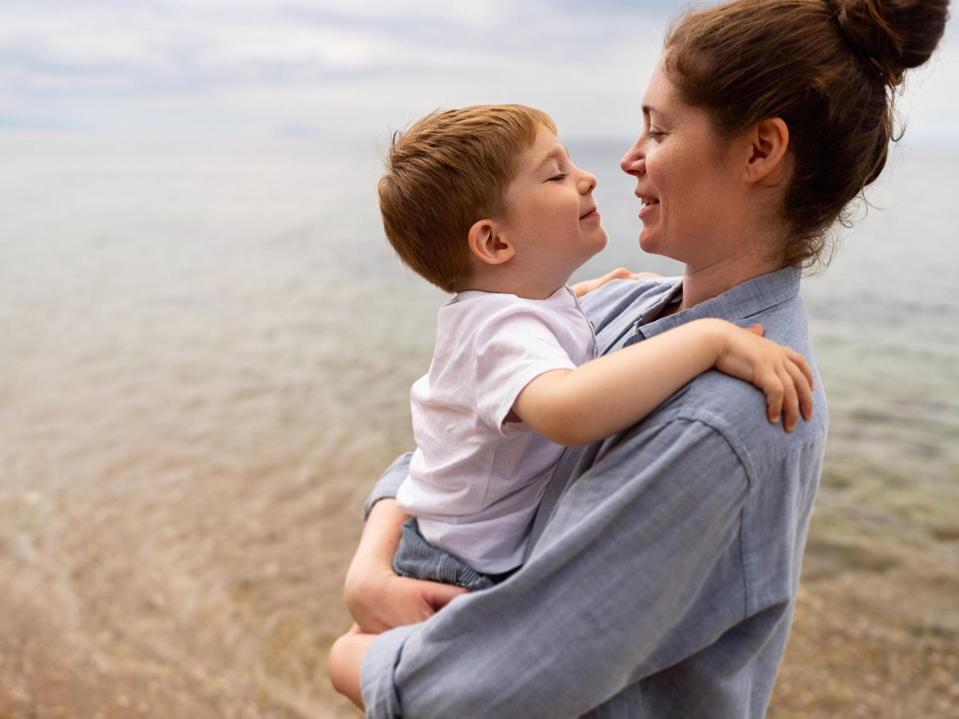 Mutter hält Sohn am Strand im Arm