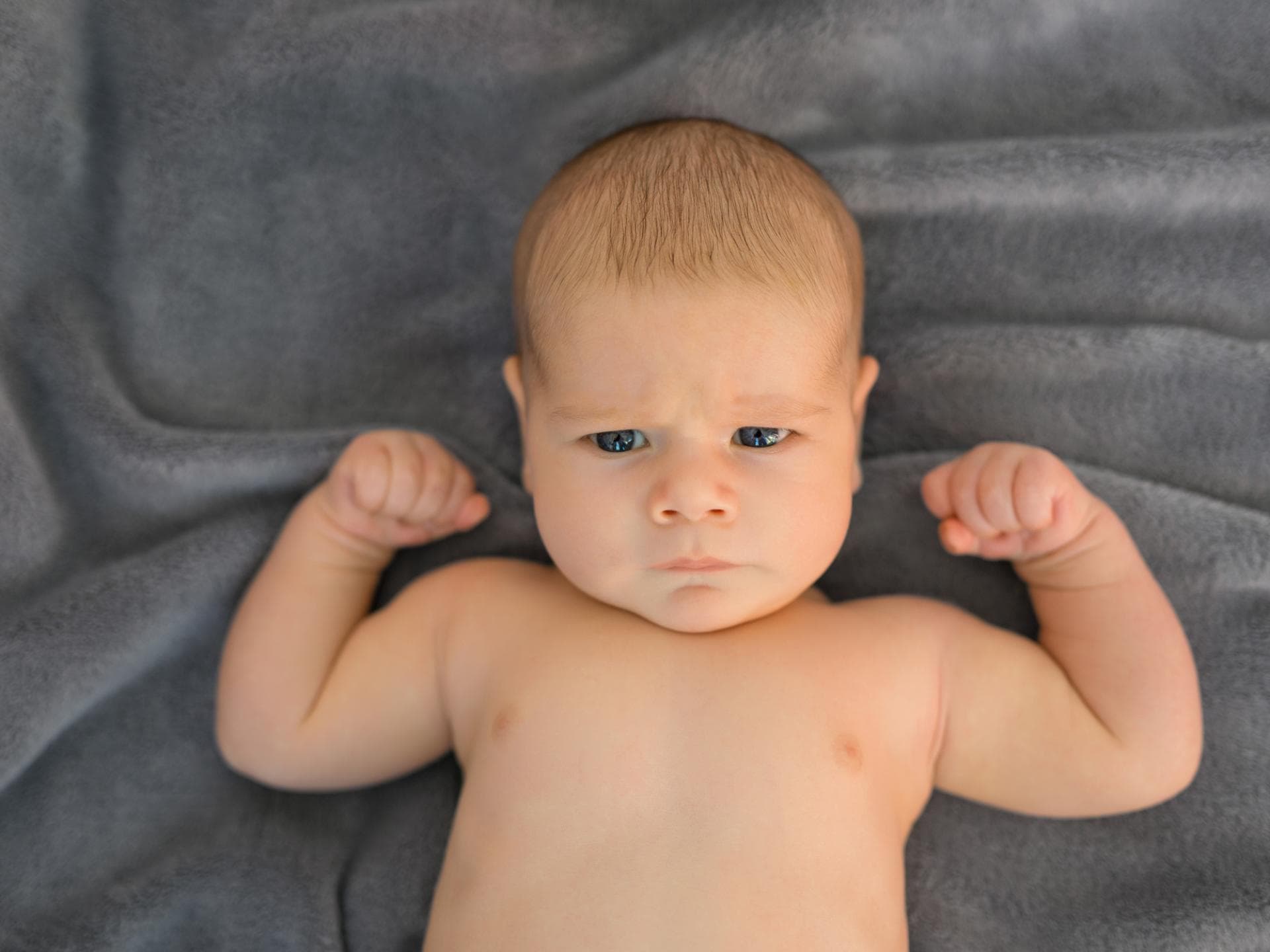 Kleine Sportskanonen brauchen einen Vornamen für Champions. Starkes Baby liegt auf einer Decke