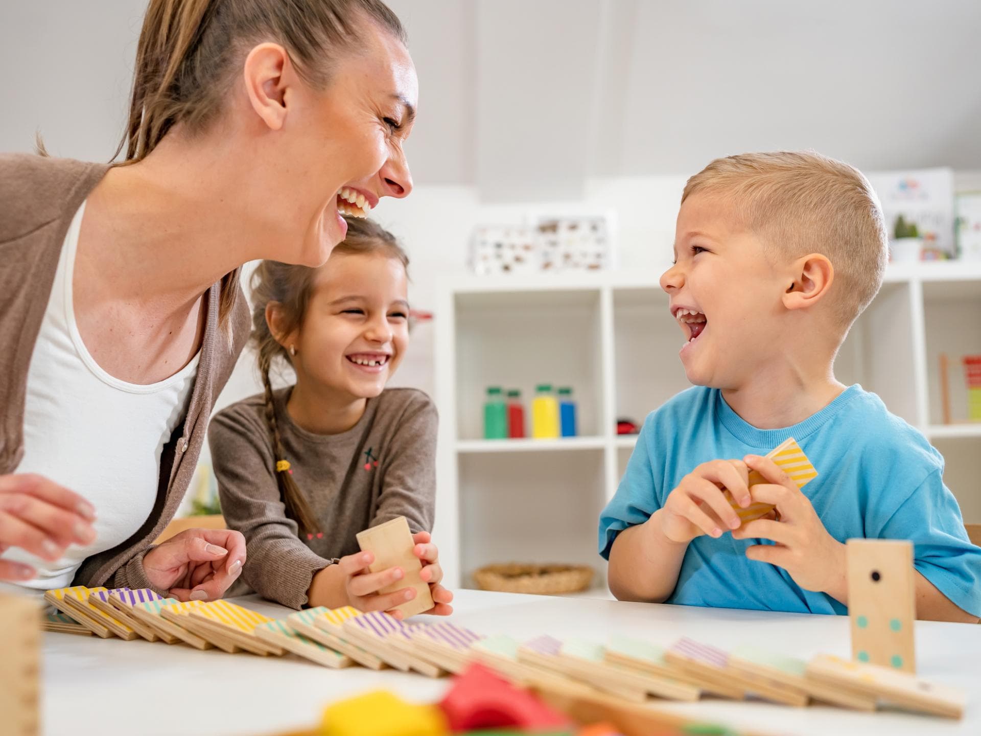 Der Übergang von Krippe zu Kindergarten kann von vielen Gefühlen begleitet werden Eine Erzieherin, die mit einem Kind gemeinsam lacht