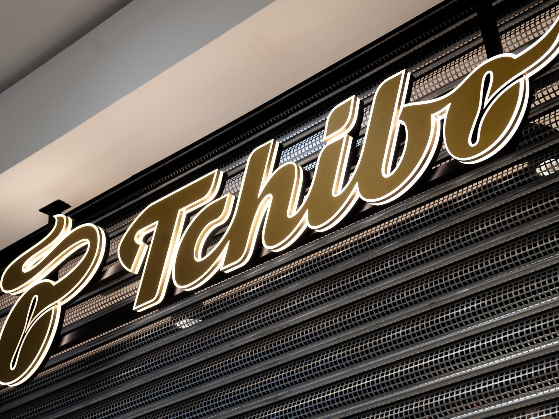 Bei Tchibo gibt es günstige Wollwalkanzüge. Das Tchibo Logo am Laden