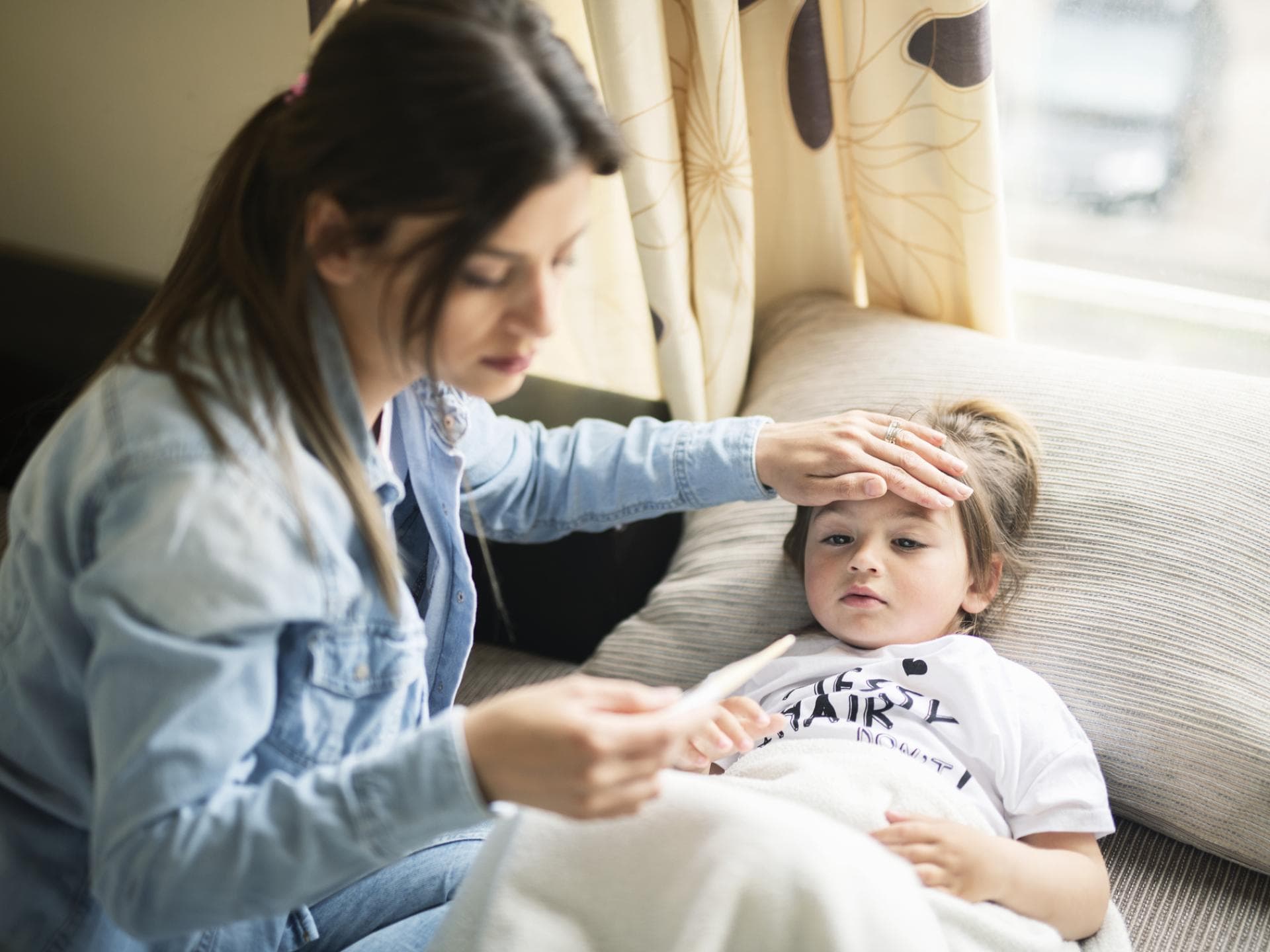 Die Fälle der Mykoplasmen-Pneumonien bei Kindern steigen. Mutter misst Fieber bei ihrem Sohn.