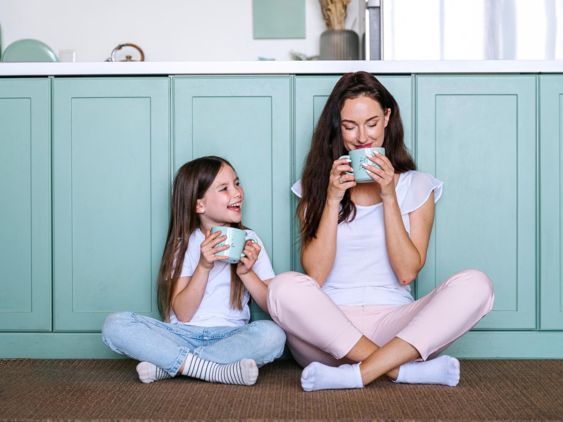 Als Mama den Kopf frei zu bekommen ist eine Herausforderung. Mama und Tochter sitzen in der Küche und trinken aus Tassen.
