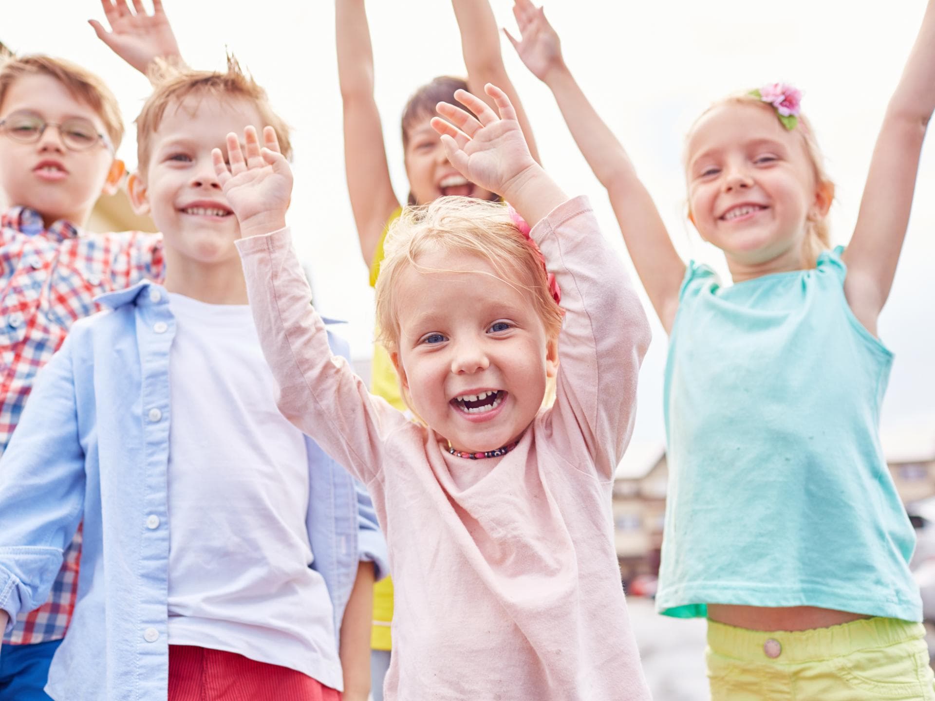 Am Weltkindertag wird auf die Rechte von Kindern weltweit aufmerksam gemacht. Lachende Kinder mit erhobenen Armen.