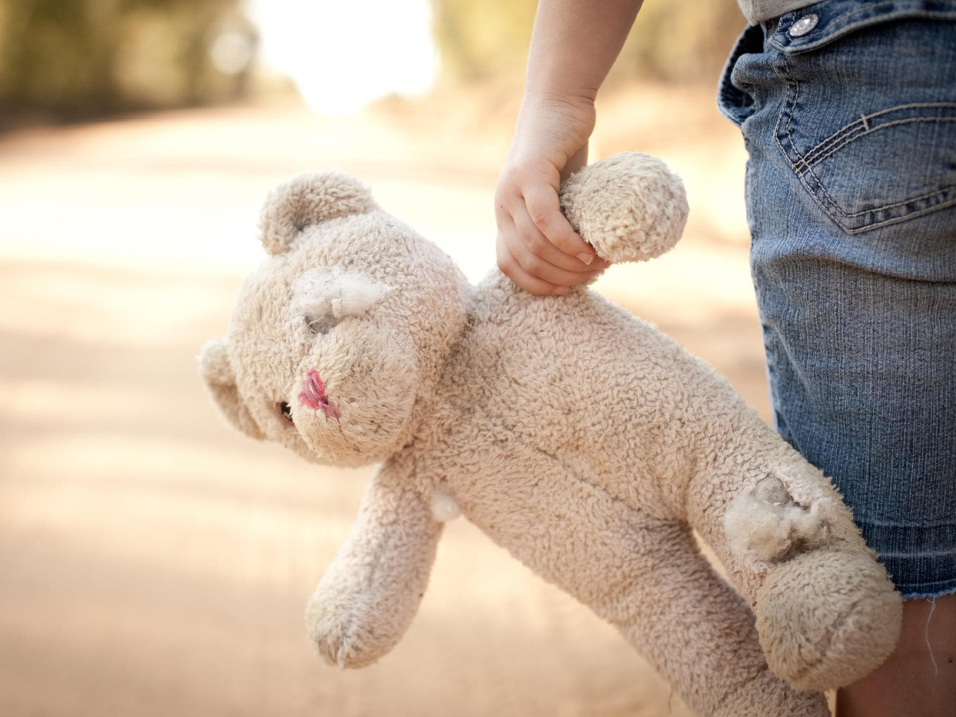 Kindeswohlgefährdungen auf neuem Höchststand Ein Kind, das einen zerfetzten Teddy hält.