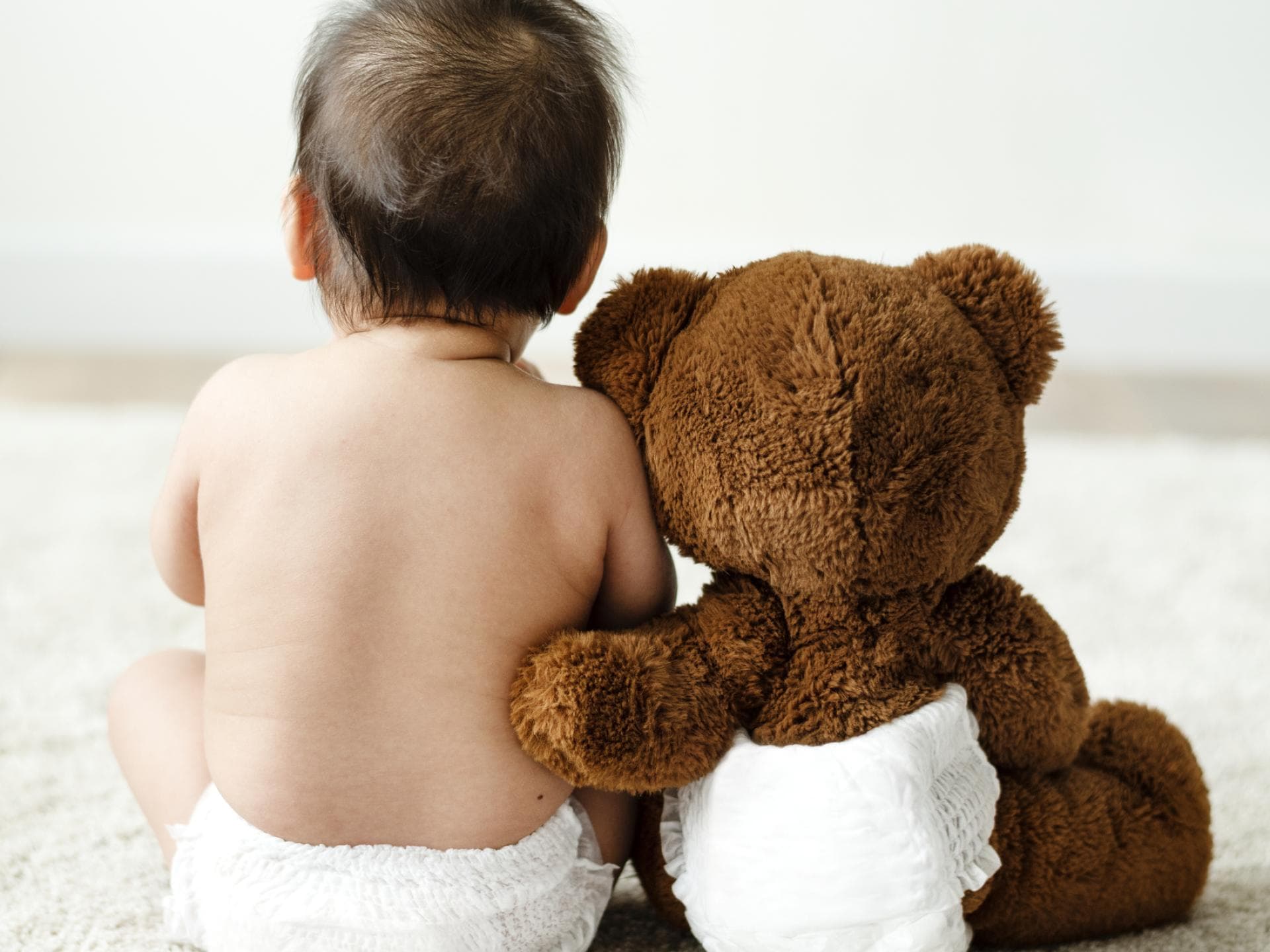 Windeln gibt es jetzt im Angebot. Baby und Kuschelbär mit Windeln.