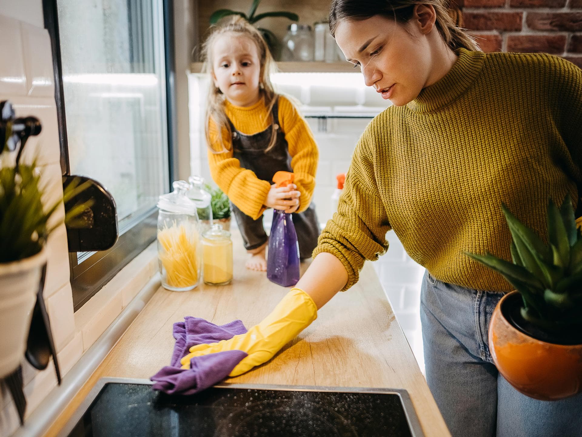 Eltern sind im Schnitt über zwei Stunden pro Woche mit Hausarbeit beschäftigt. Mutter putzt die Küche mit ihrer Tochter.