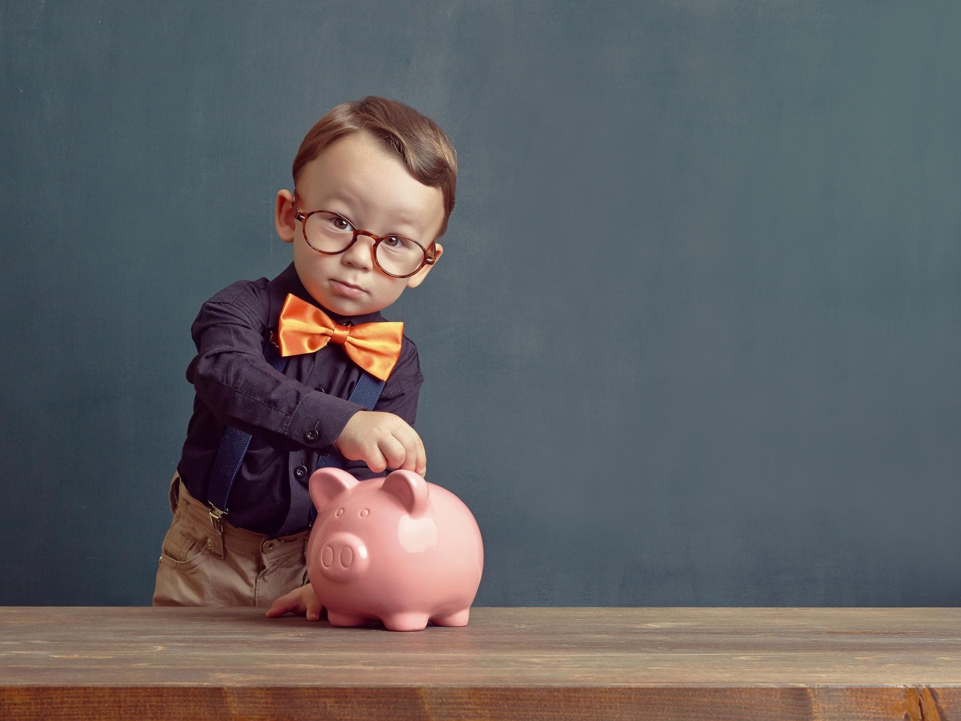 Der richtige Vorname ist der erste Schritt zum Milliardär. Junge steckt Geld in sein Sparschwein.