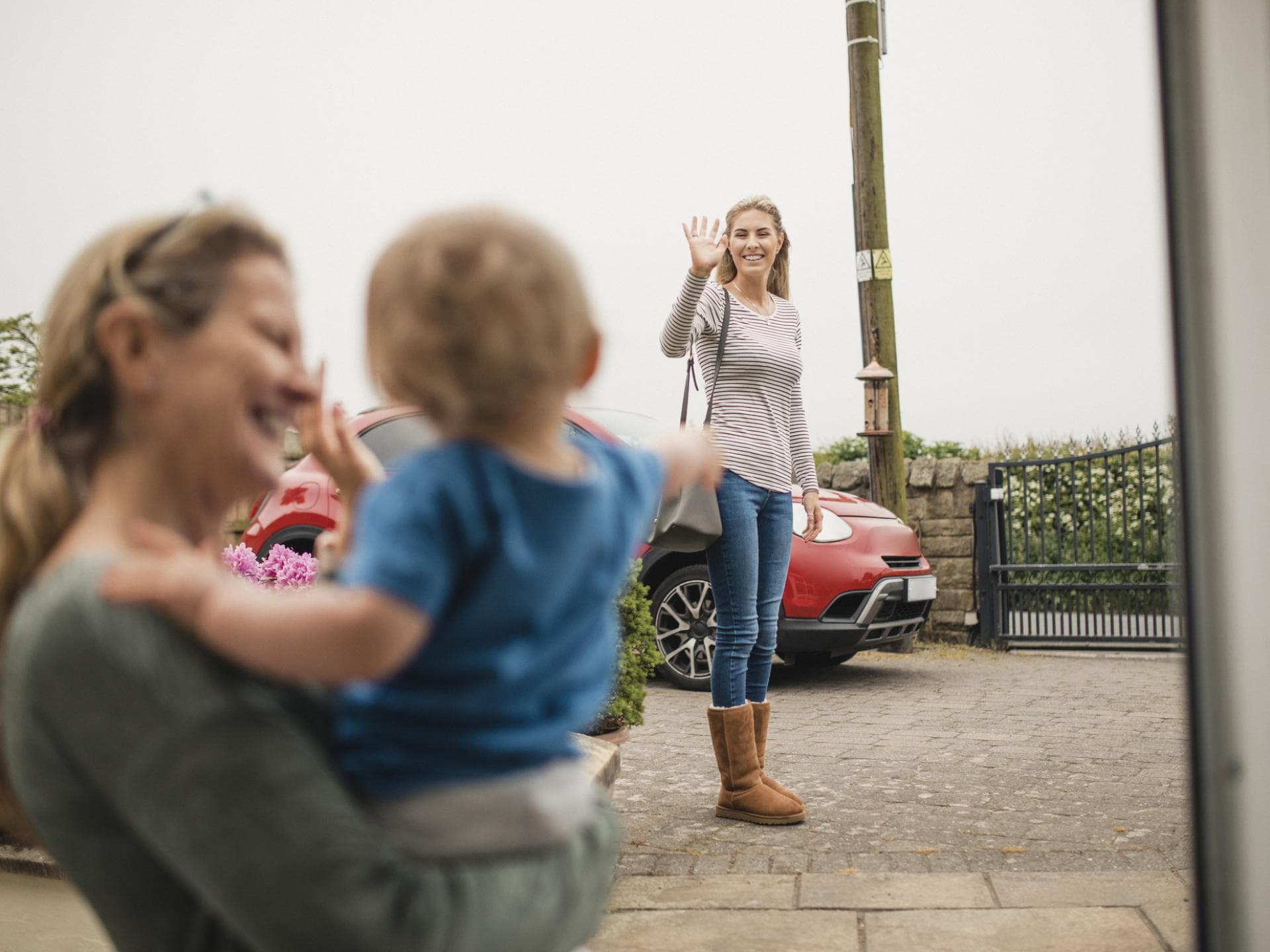 Nanny winkt mit Kleinkind der Mutter.