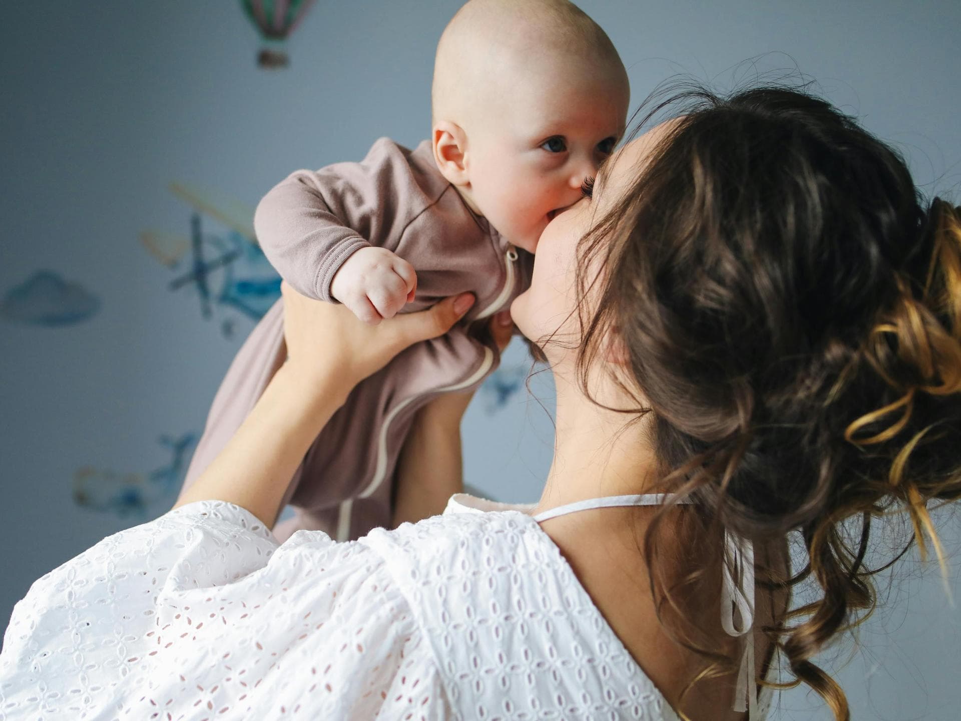 Eine Mama hebt ihr Baby hoch. 