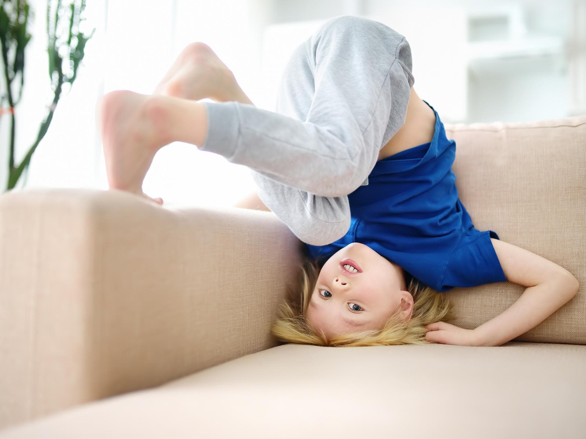 Junge macht Kopfstand auf dem Sofa.