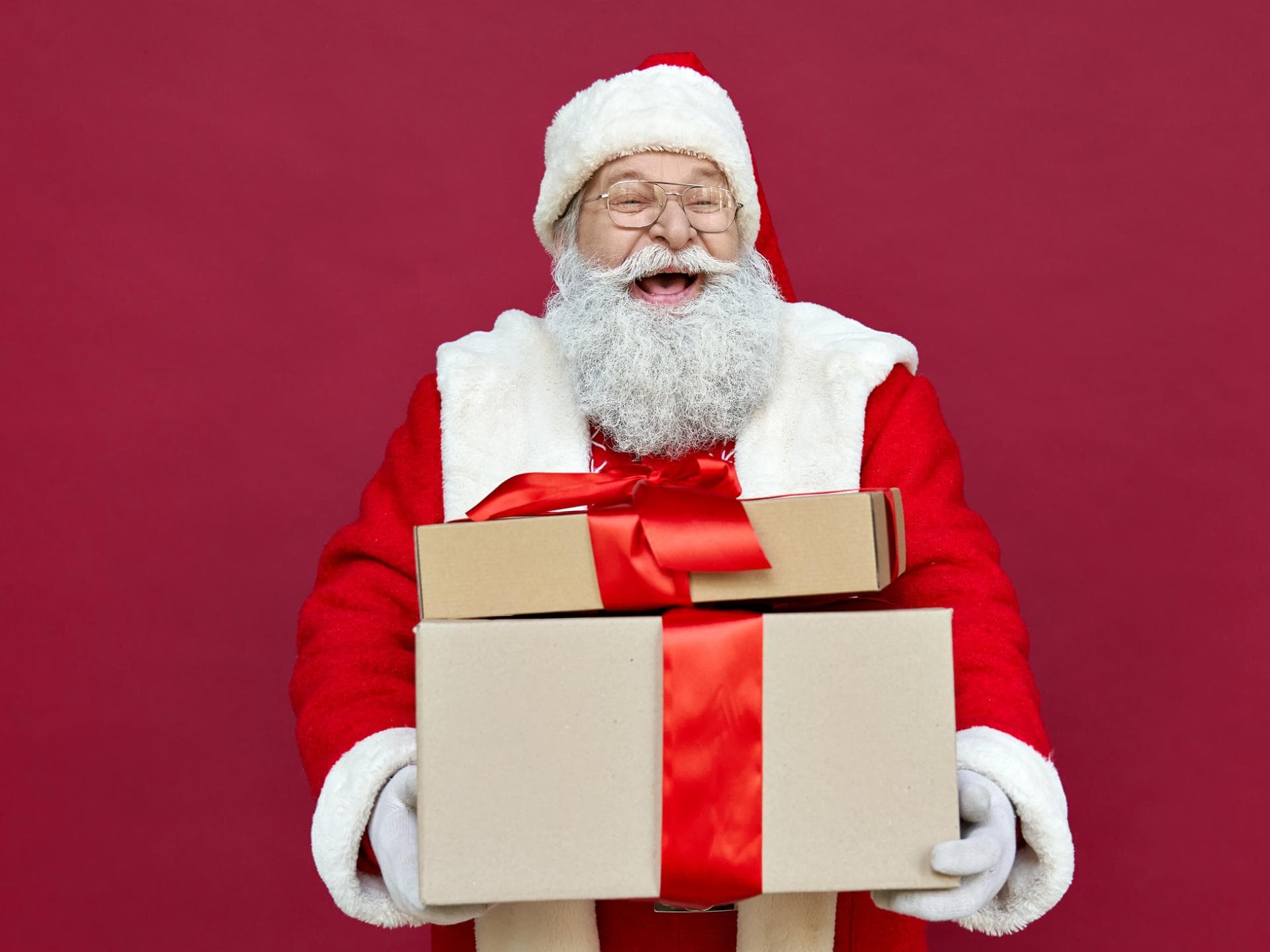 Ein Nikolaus mit Geschenken im Arm lacht aus vollem Herzen. 