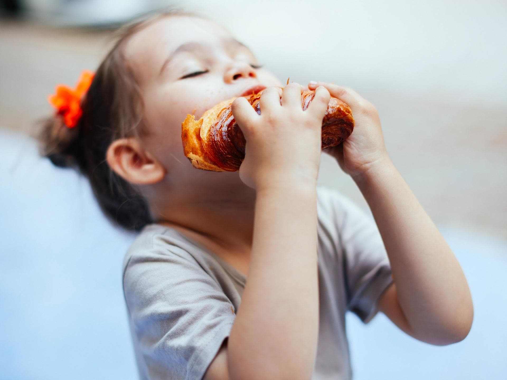 Ein Mädchen beißt in ein Croissant.